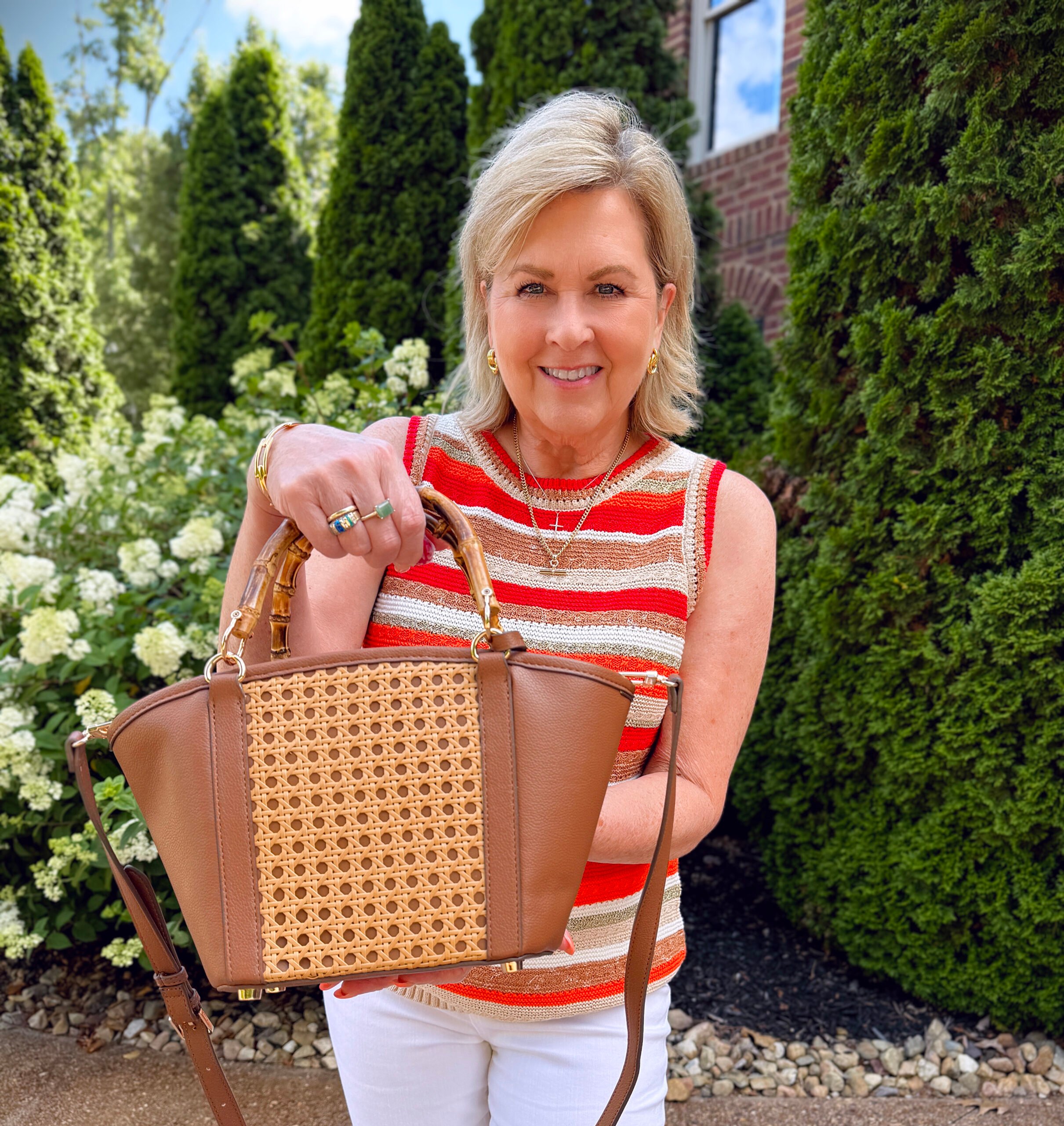 Tania wearing a striped summer tank sweater with a cane handbag