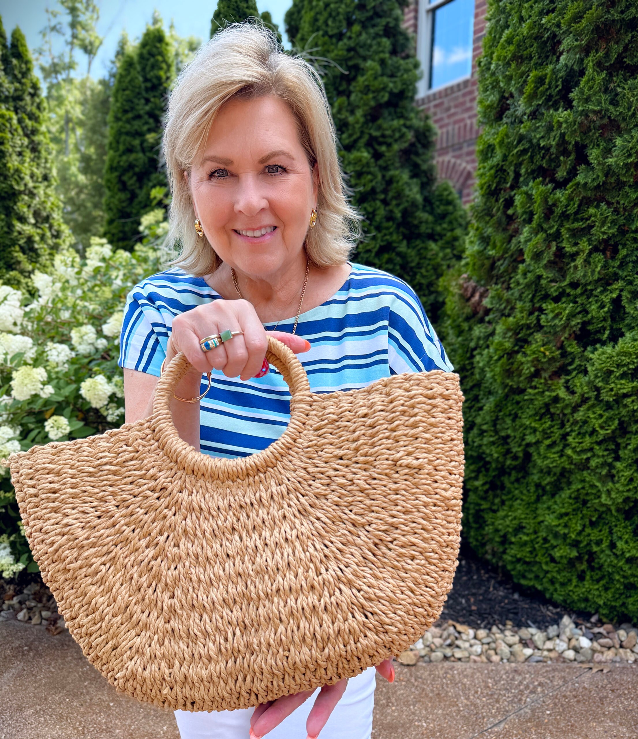 Tania wearing a striped summer tee with a straw handbag