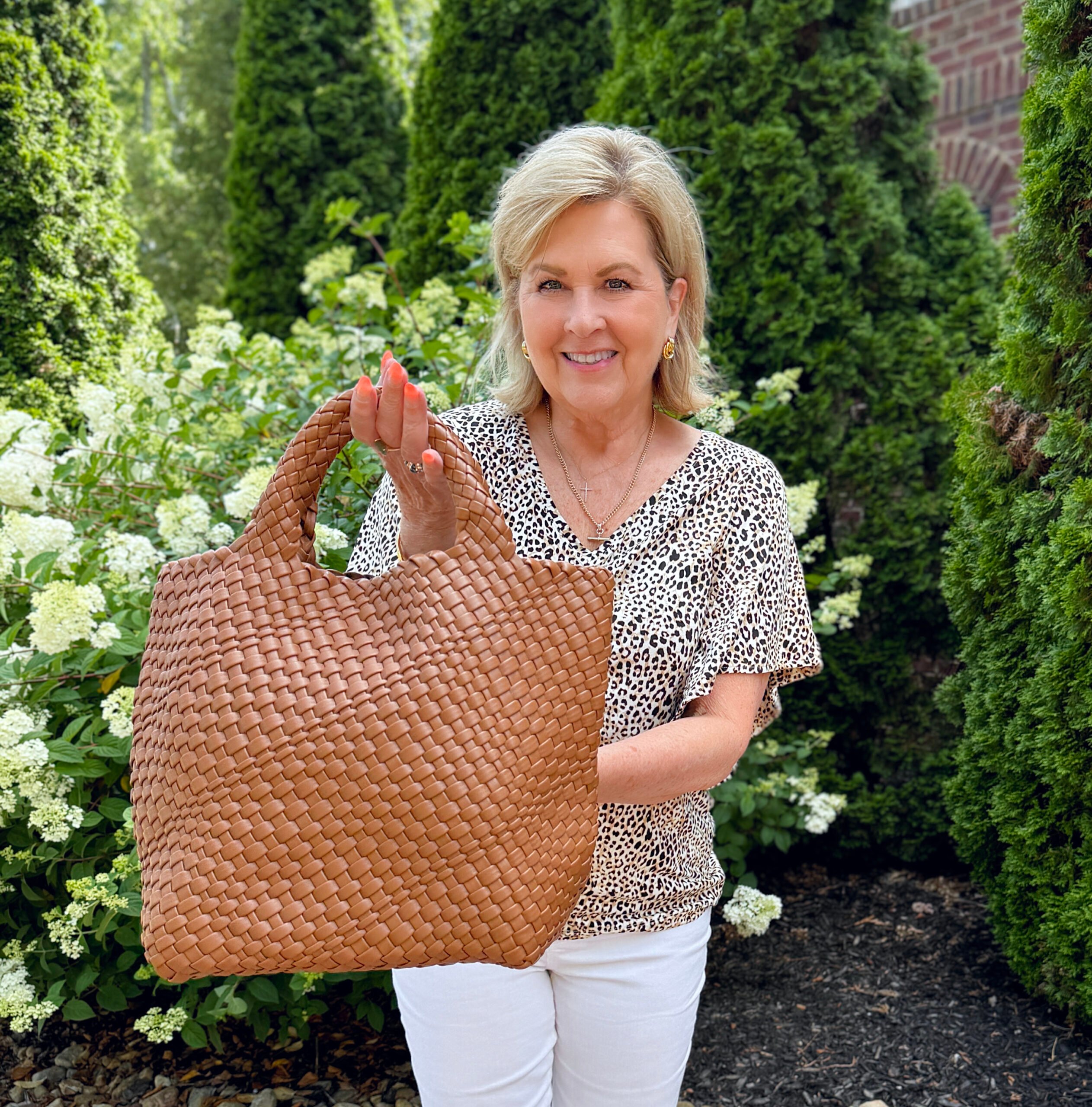Tania wearing a animal print top with a woven handbag