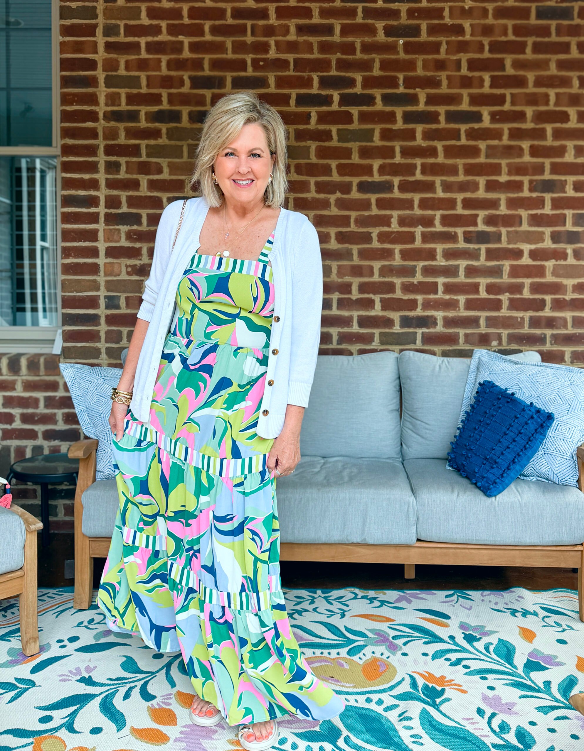 Tania wearing a pink, blue, white and green maxi dress from Amazon in front of a couch and a brick wall