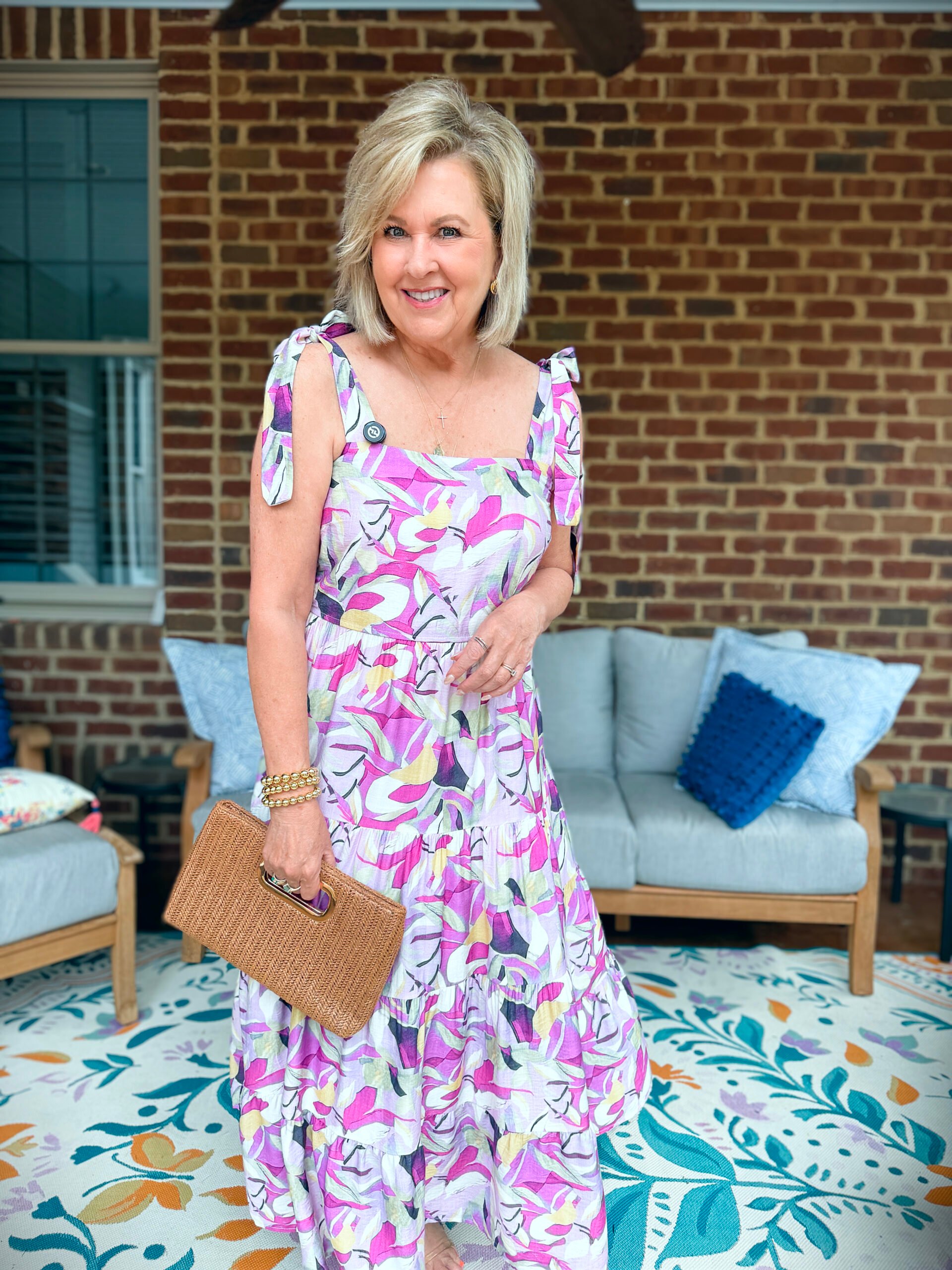 Tania wearing a purple, lilac, and yellow maxi dress from Amazon and holding a straw clutch