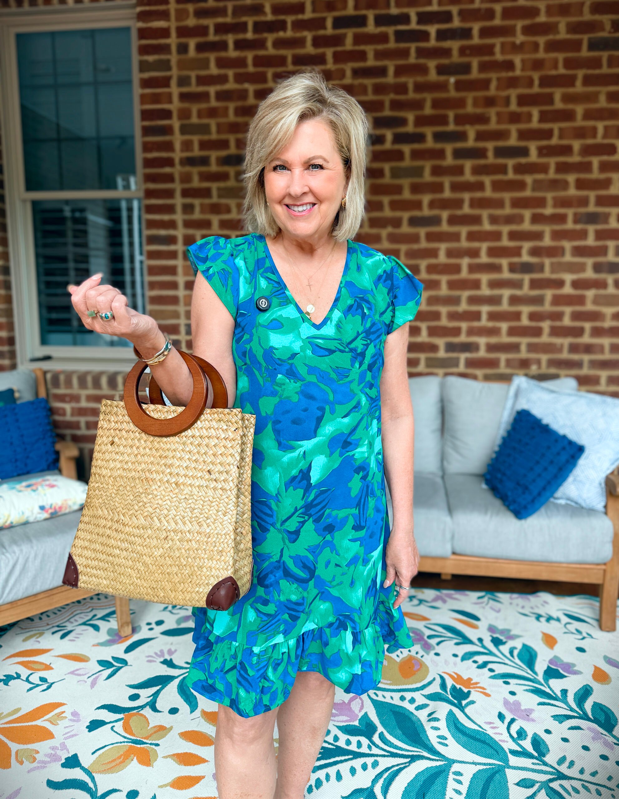 Tania wearing a blue and green dress from Amazon in front of a brick wall.