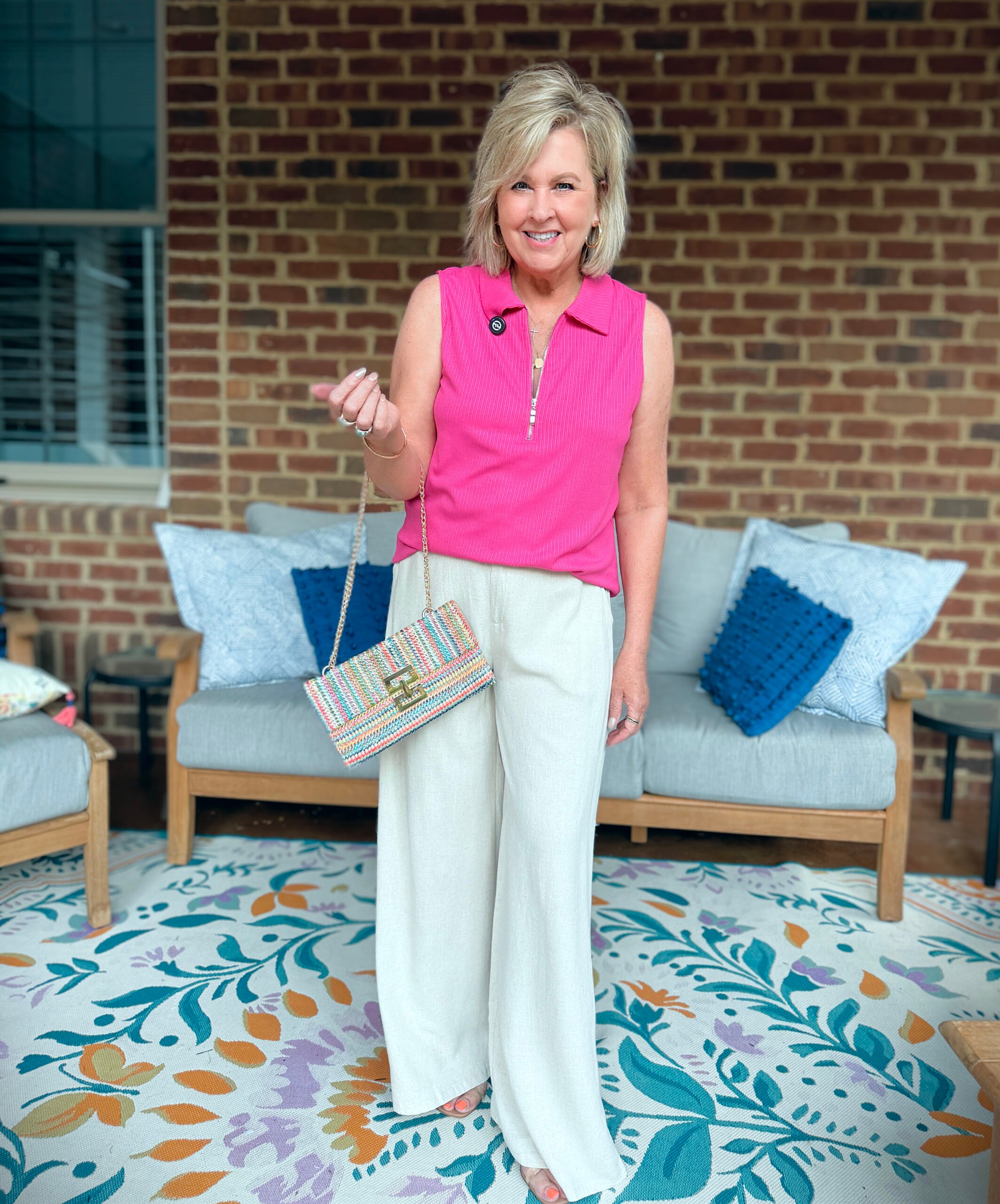 Tania wearing a bright neon pink sleeveless top with neutral linen pants