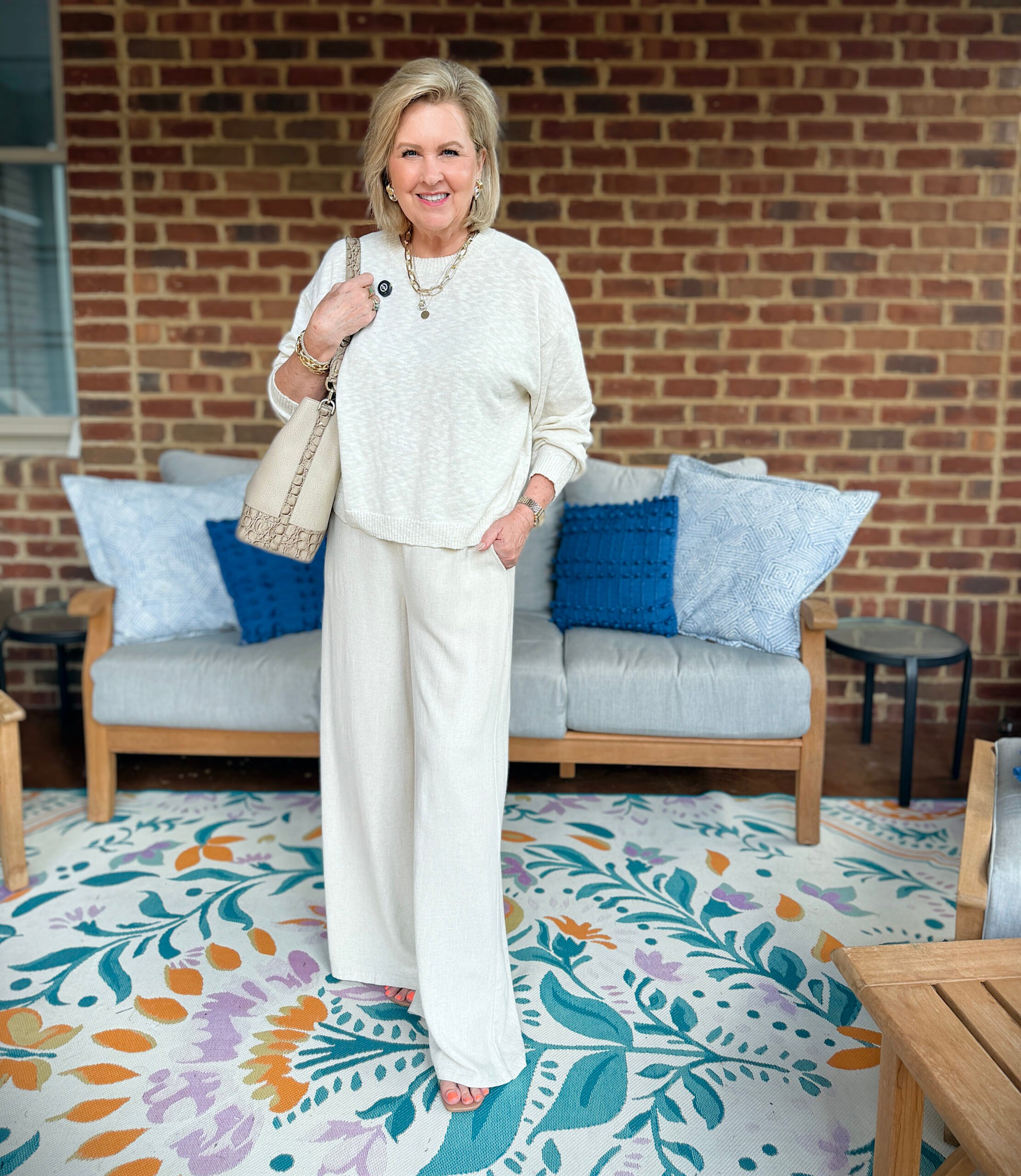 Tania is wearing a monochromatic outfit in front of a couch on a porch