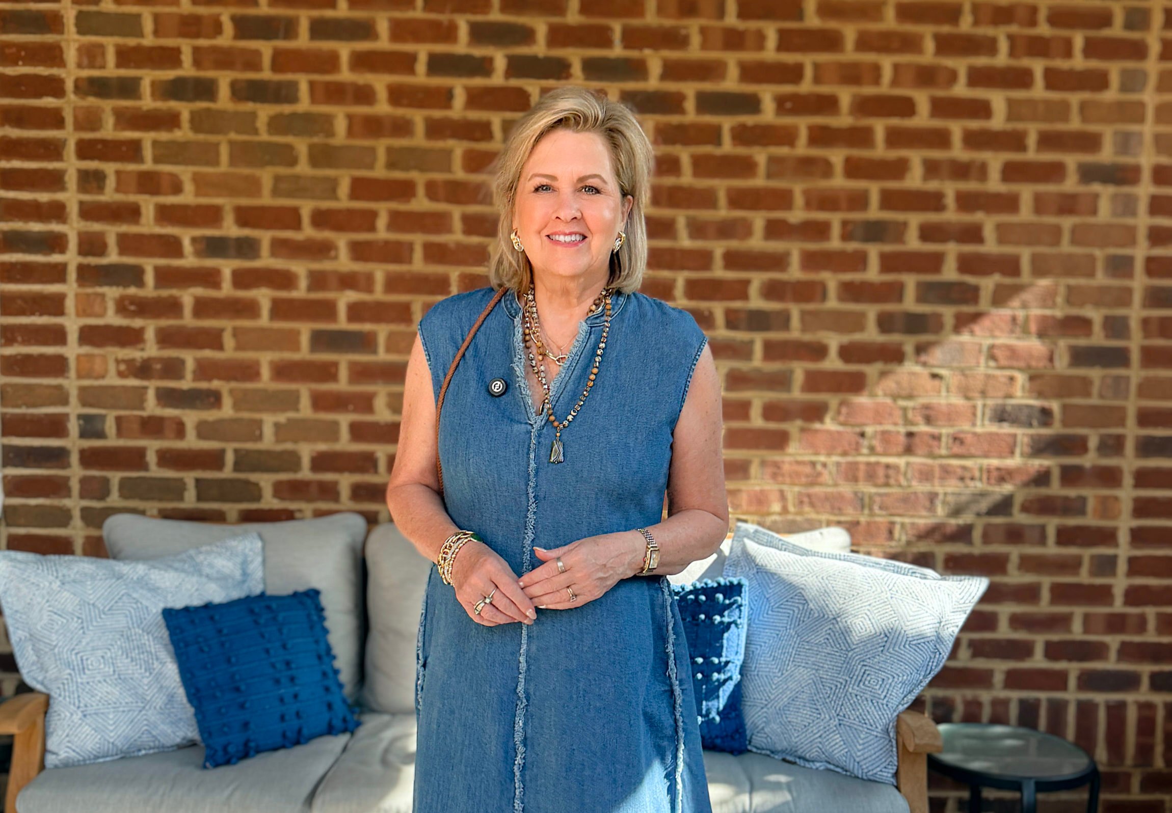 Tania is wearing a frayed denim dress on a porch