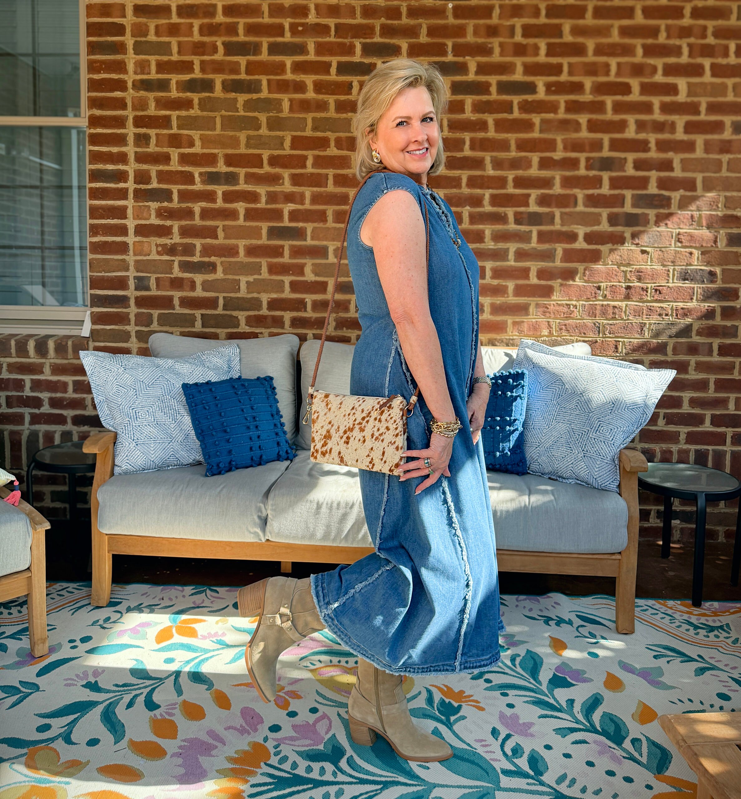Tania is wearing a frayed denim dress with cowboy booties and an animal print bag