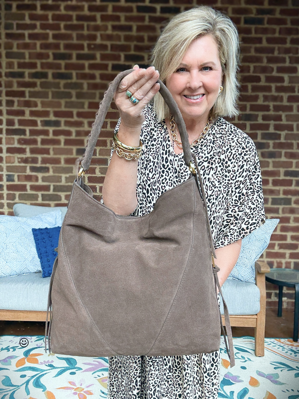 Tania wearing a leopard print kaftan holding a Rebecca Minkoff slouchy purse