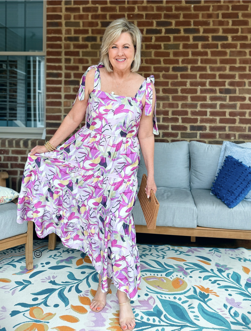 Tania wearing a purple, lilac, and yellow maxi dress from Amazon in front of a couch and a brick wall
