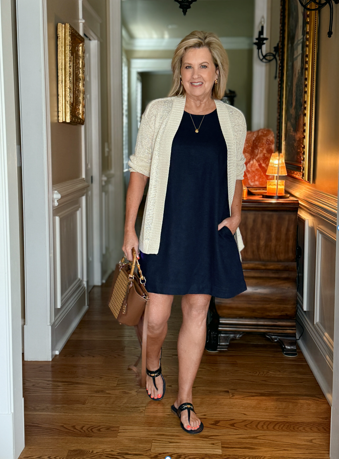 Tania wearing a versatile navy linen shift dress with a beige cardigan