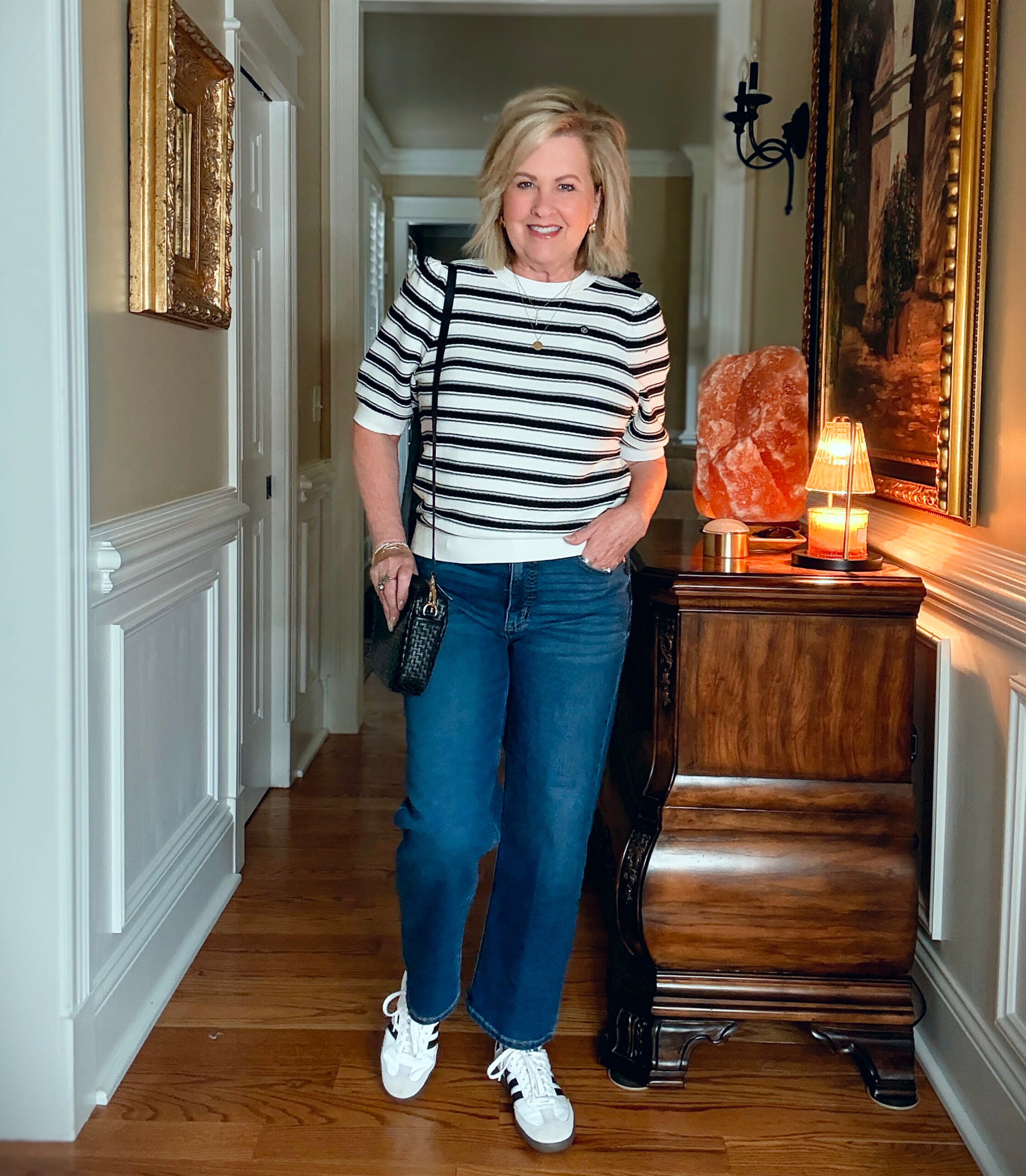 Tania is a striped sweater and dark wash jeans from Walmart. She is carrying a Quince handbag