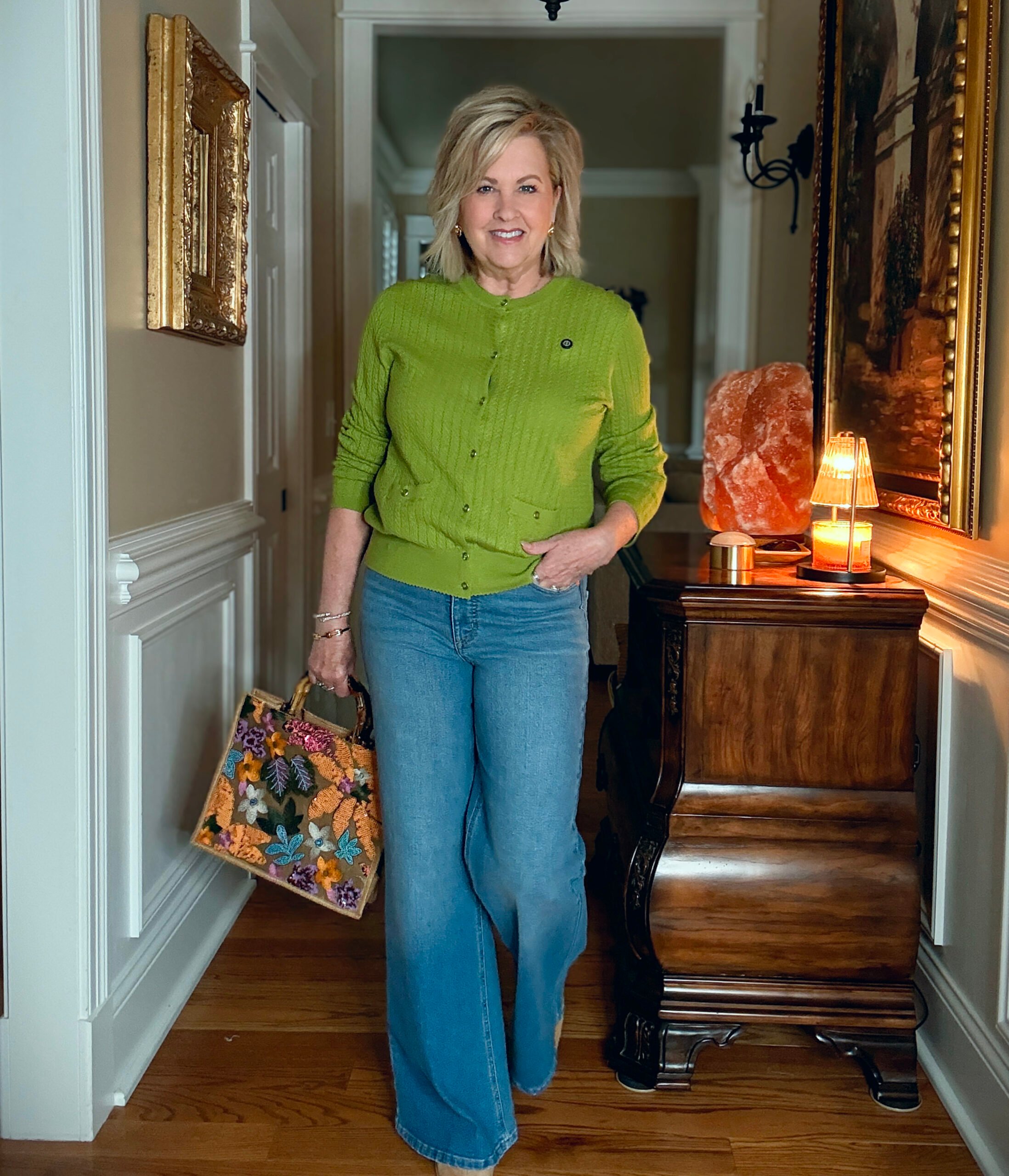 Tania is a green sweater and light wash jeans from Walmart. She is carrying a handbag from Amazon