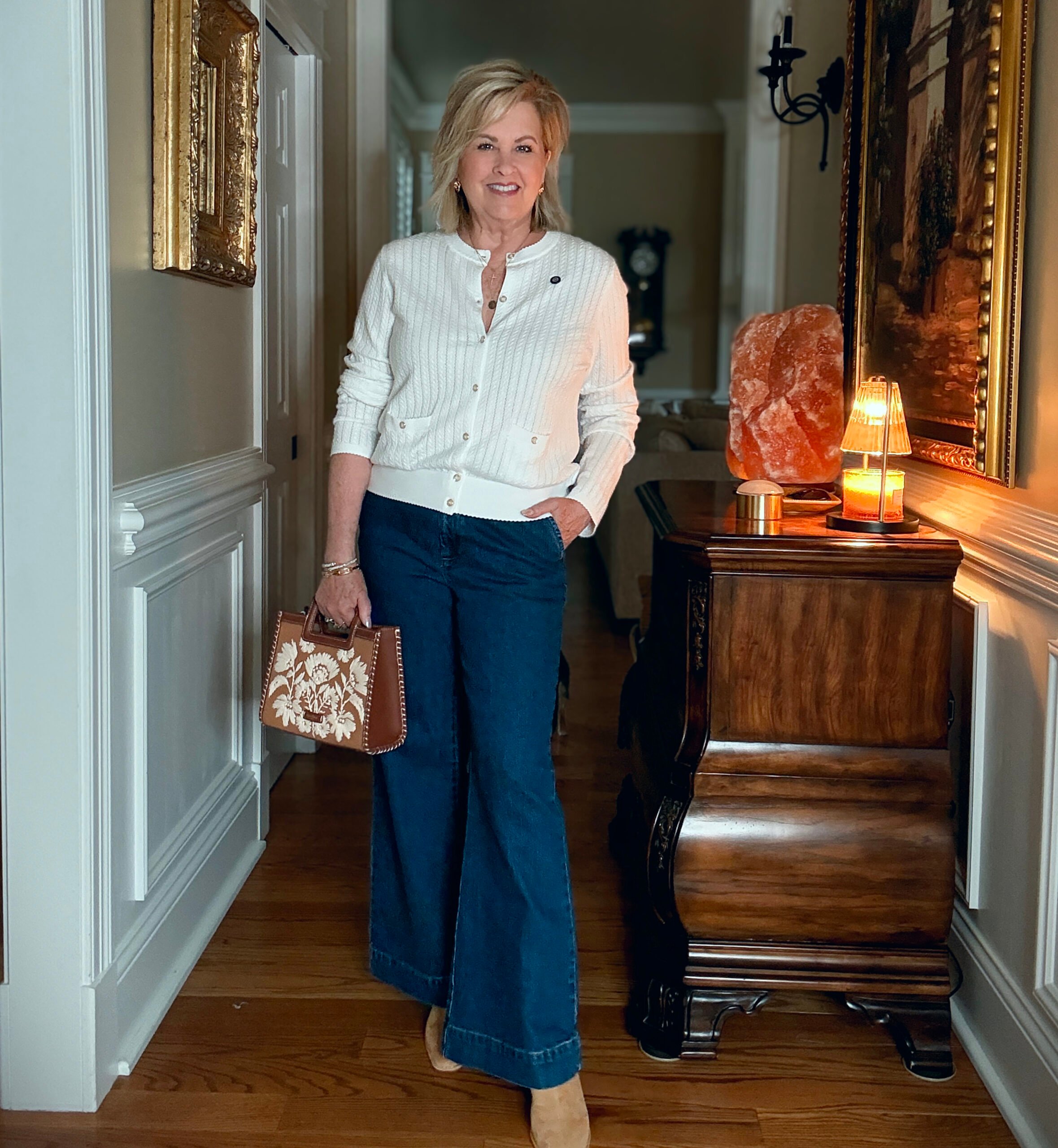 Tania is a white sweater and dark wash trouser jeans from Walmart. She is carrying a handbag from Spartina 449