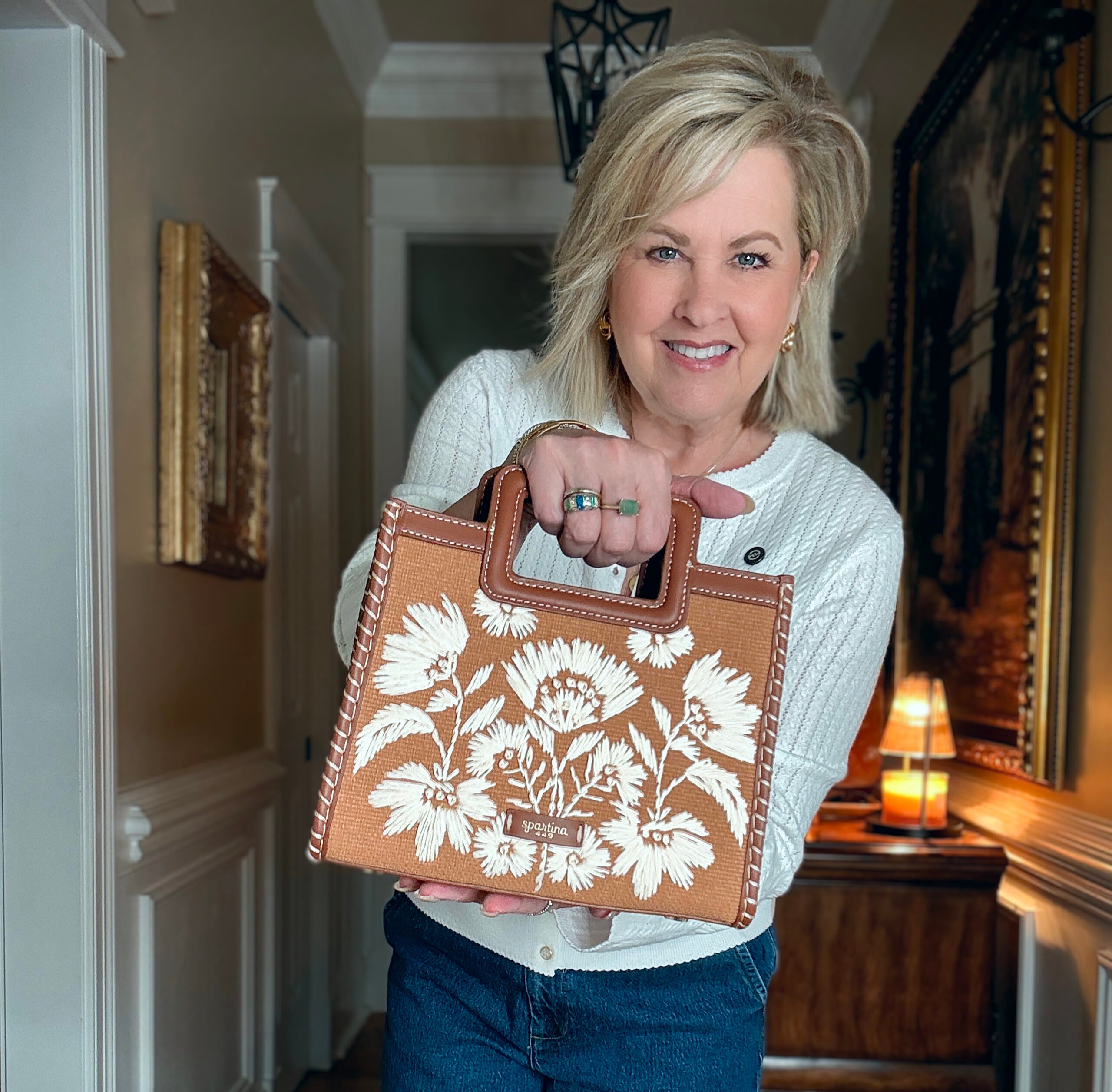 Tania is a white sweater and holding a handbag from Spartina 449
