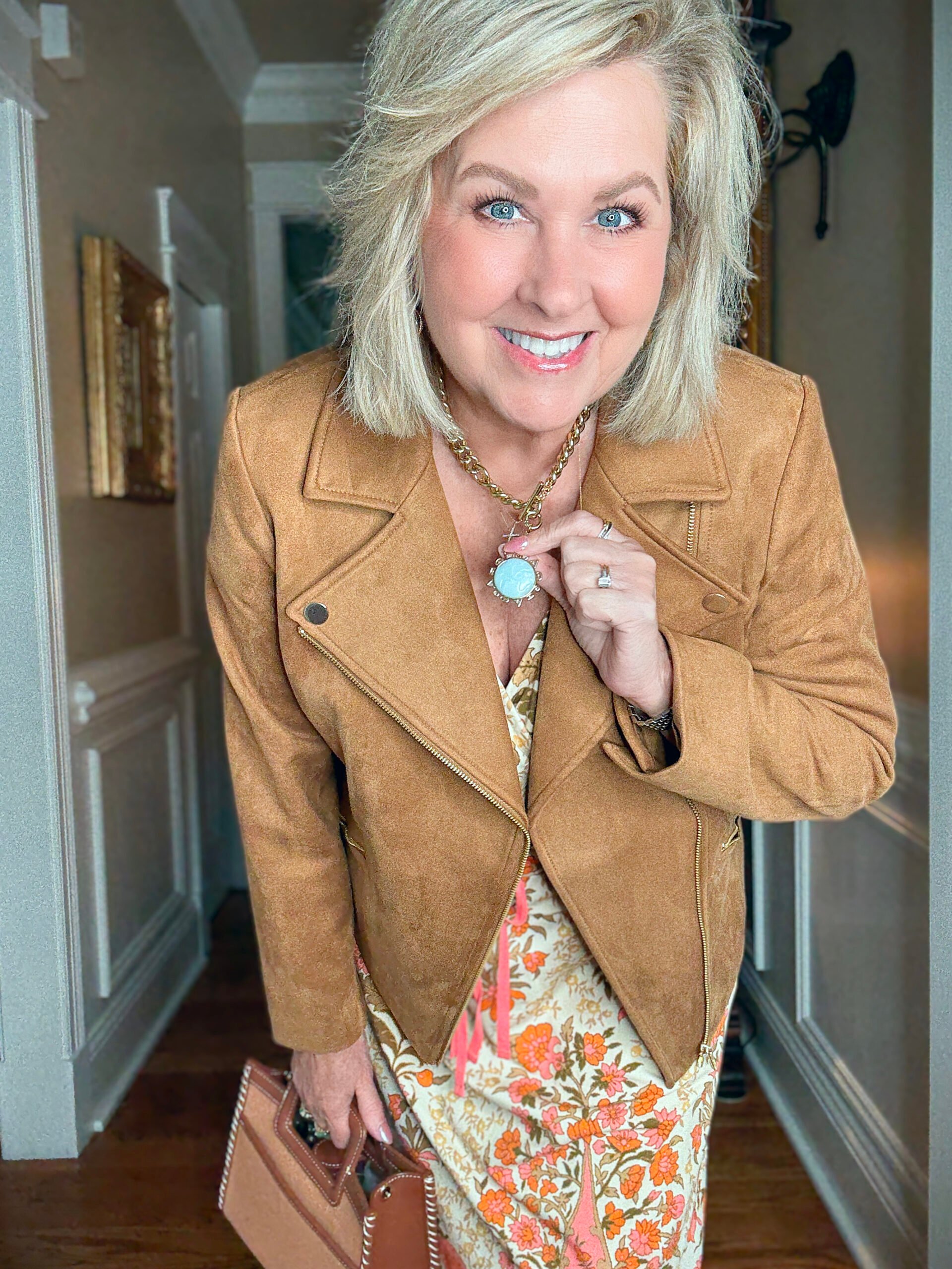 Tania Stephens showing a blue necklace with a faux suede jacket