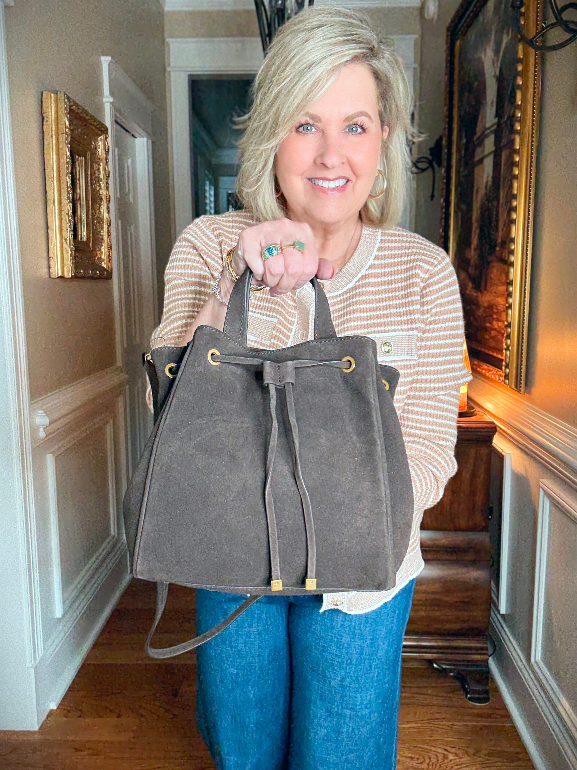 Tania is wearing a camel plaid jacket with a suede bucket bag