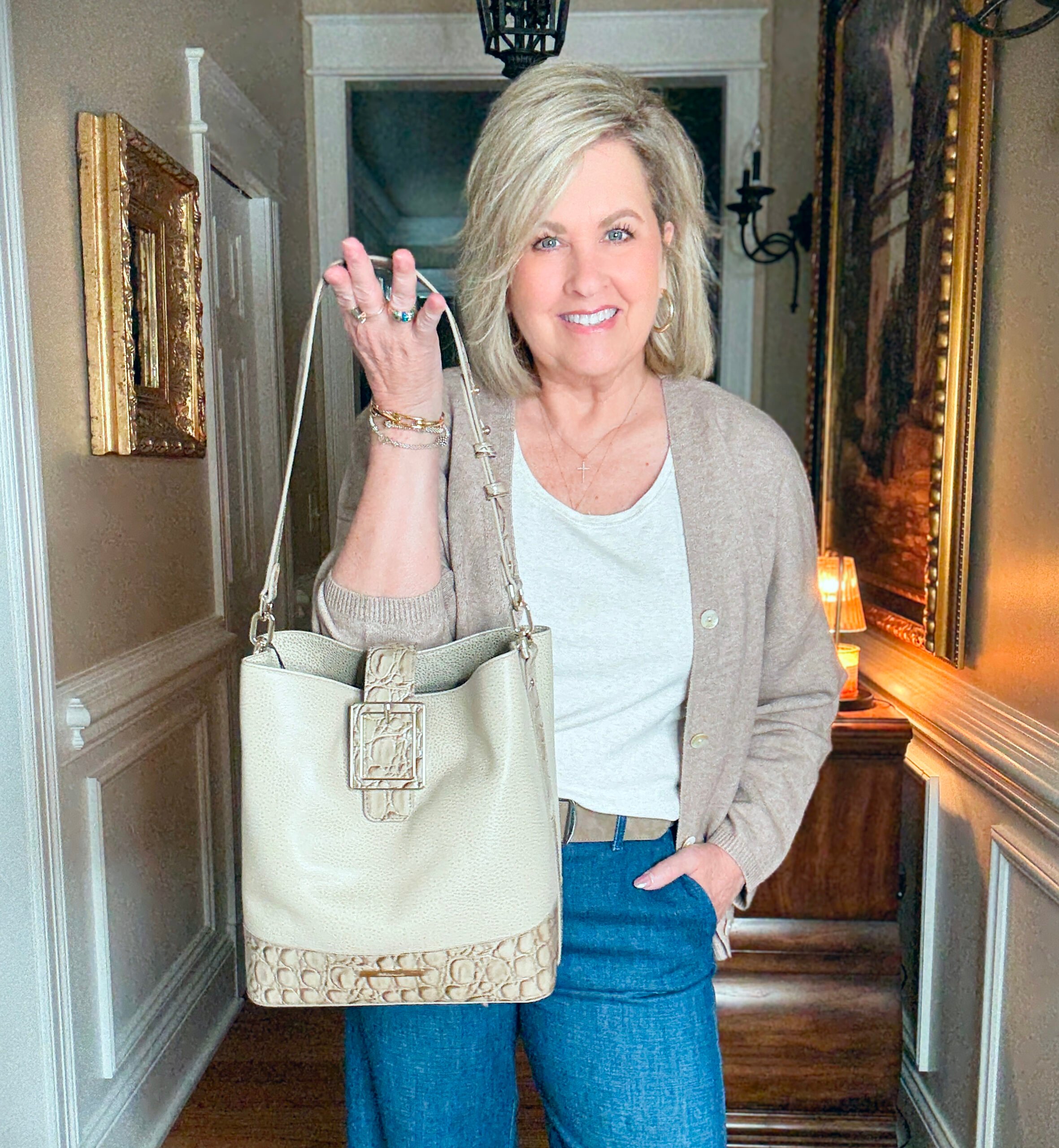 Tania is wearing an oversized sweater with a Brahmin bag