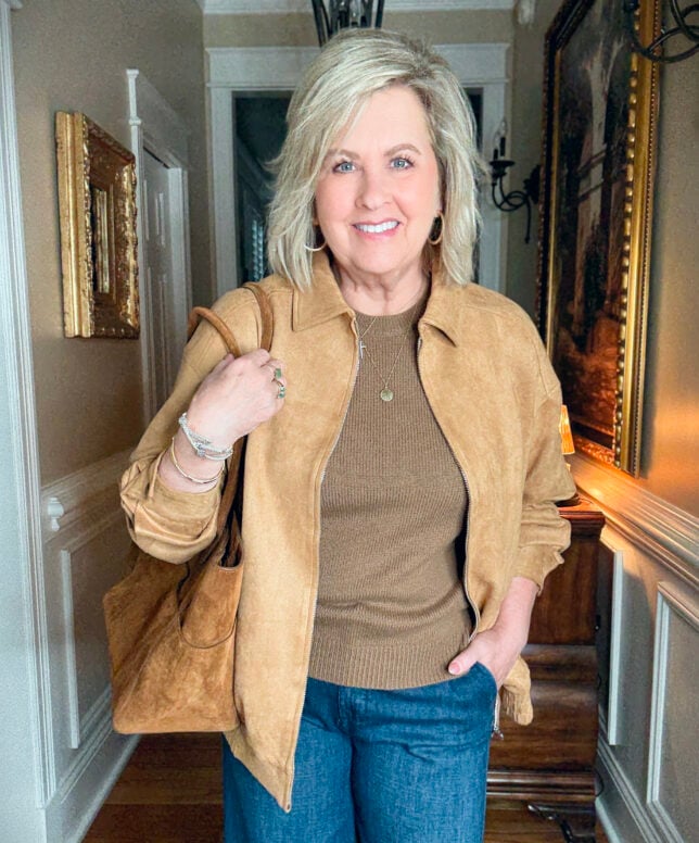 Tania is wearing a camel jacket and a brown sweater