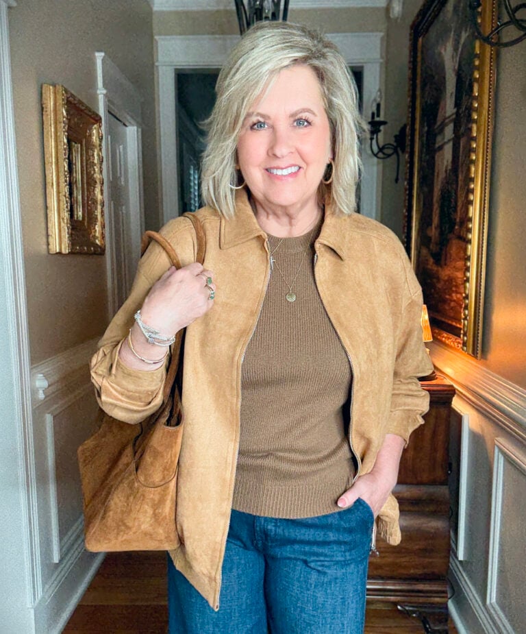 Tania is wearing a camel jacket and a brown sweater