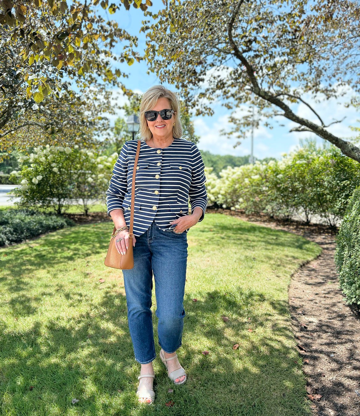 Tania wearing jeans and a striped knit cardigan from Talbots on a grassy field