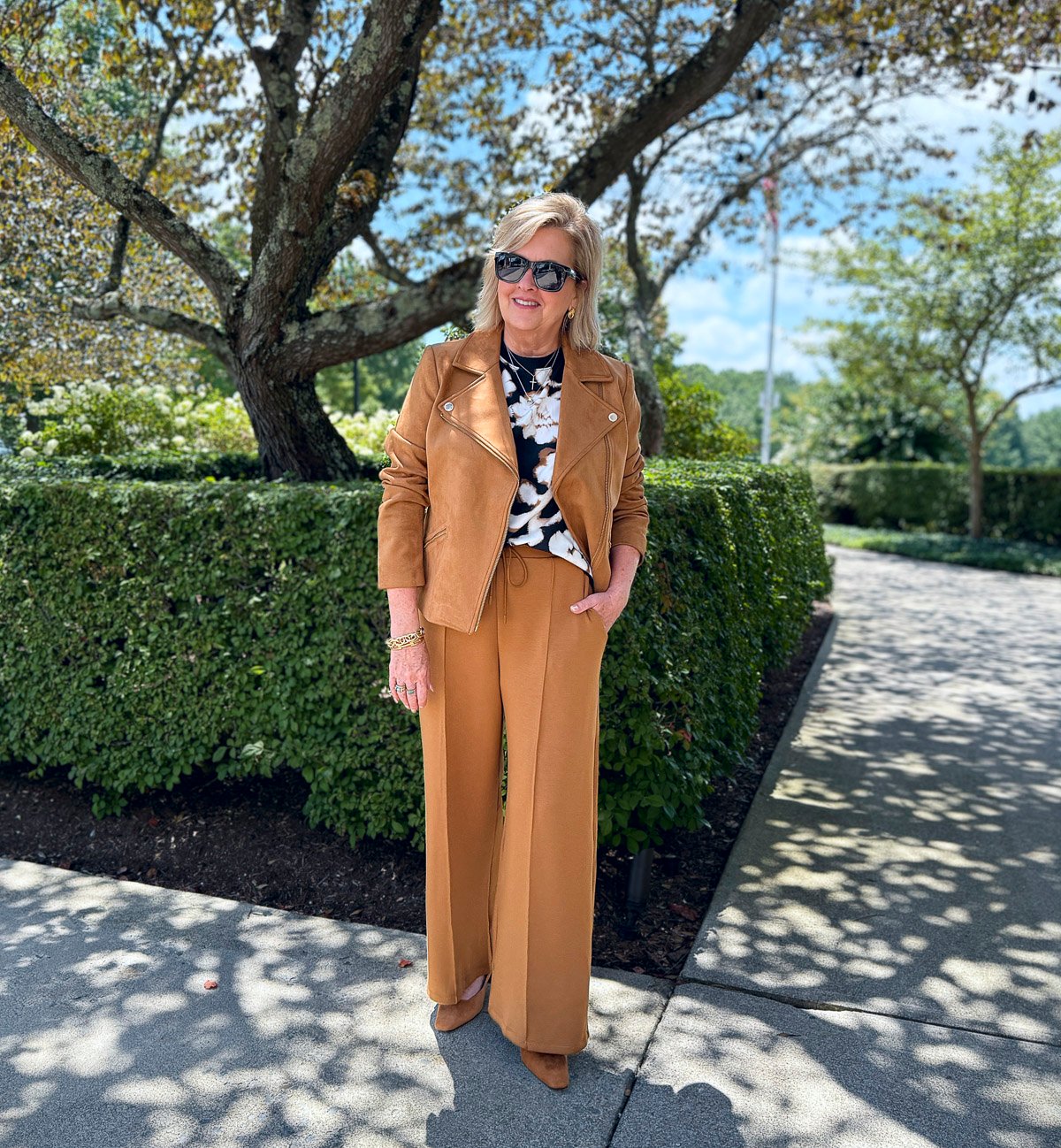 Tania wearing an air-knit short sleeve floral top with a faux suede moto jacket and pleated pants from Talbots 