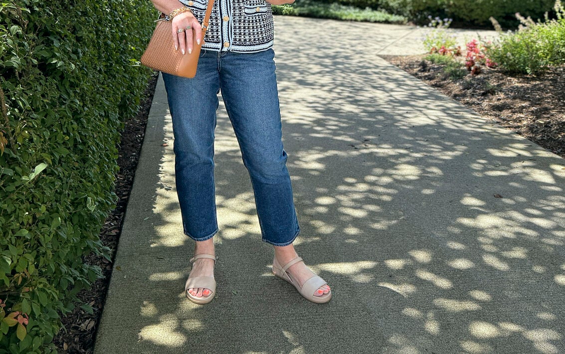 Close-up of slim straight ankle jeans paired with striped jacket and leather bag