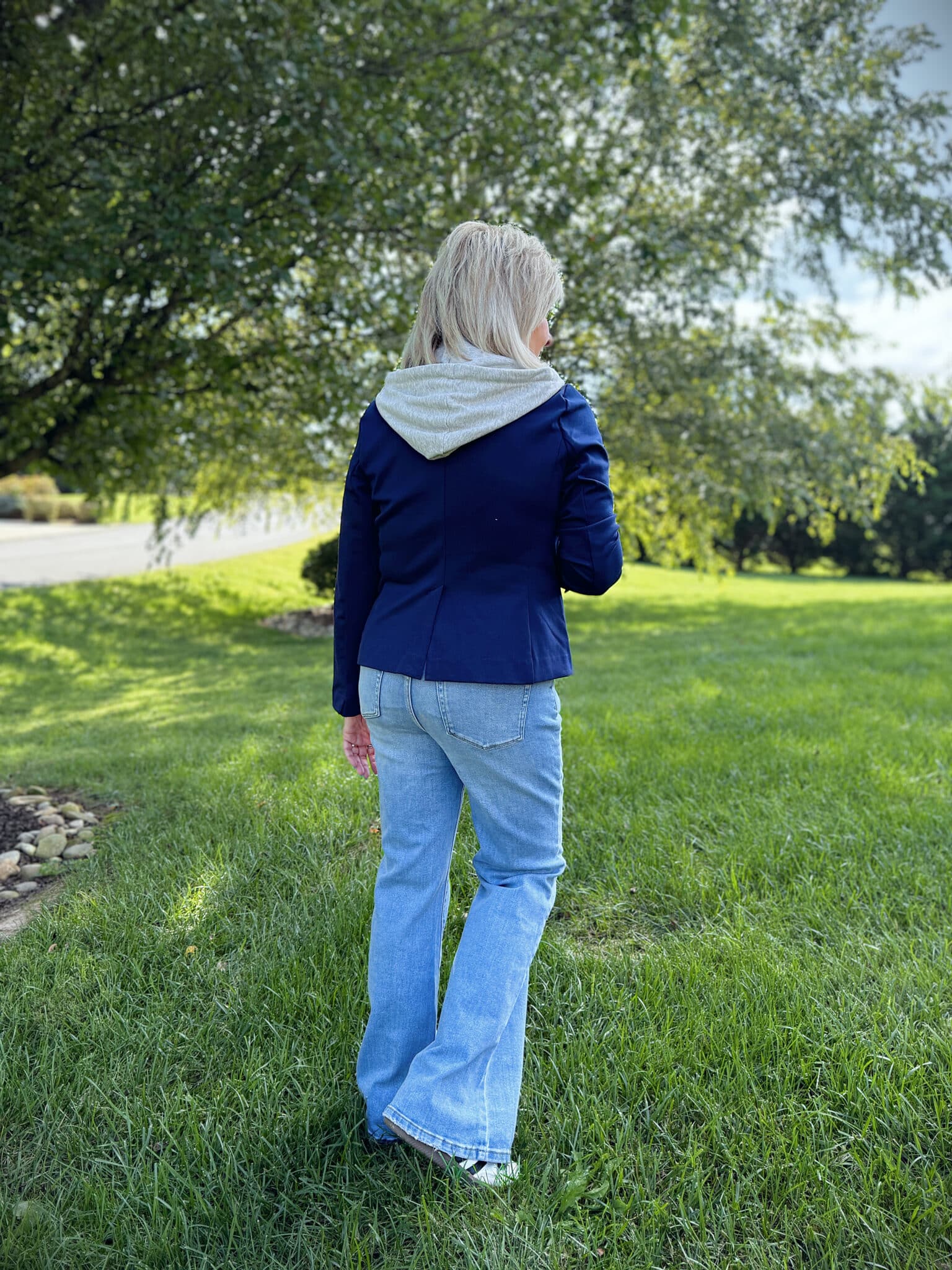 Woman over 50 standing in a grassy field showing the back of a navy and gray hoodie from Kohl's