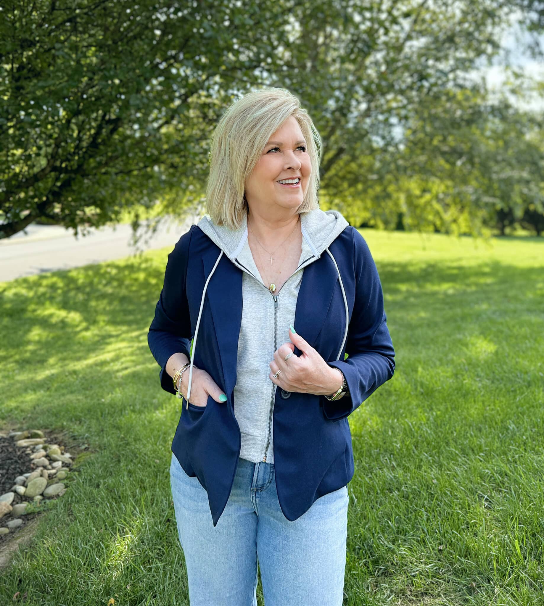 Woman over 50 standing in a grassy field in a navy and gray hoodie from Kohl's