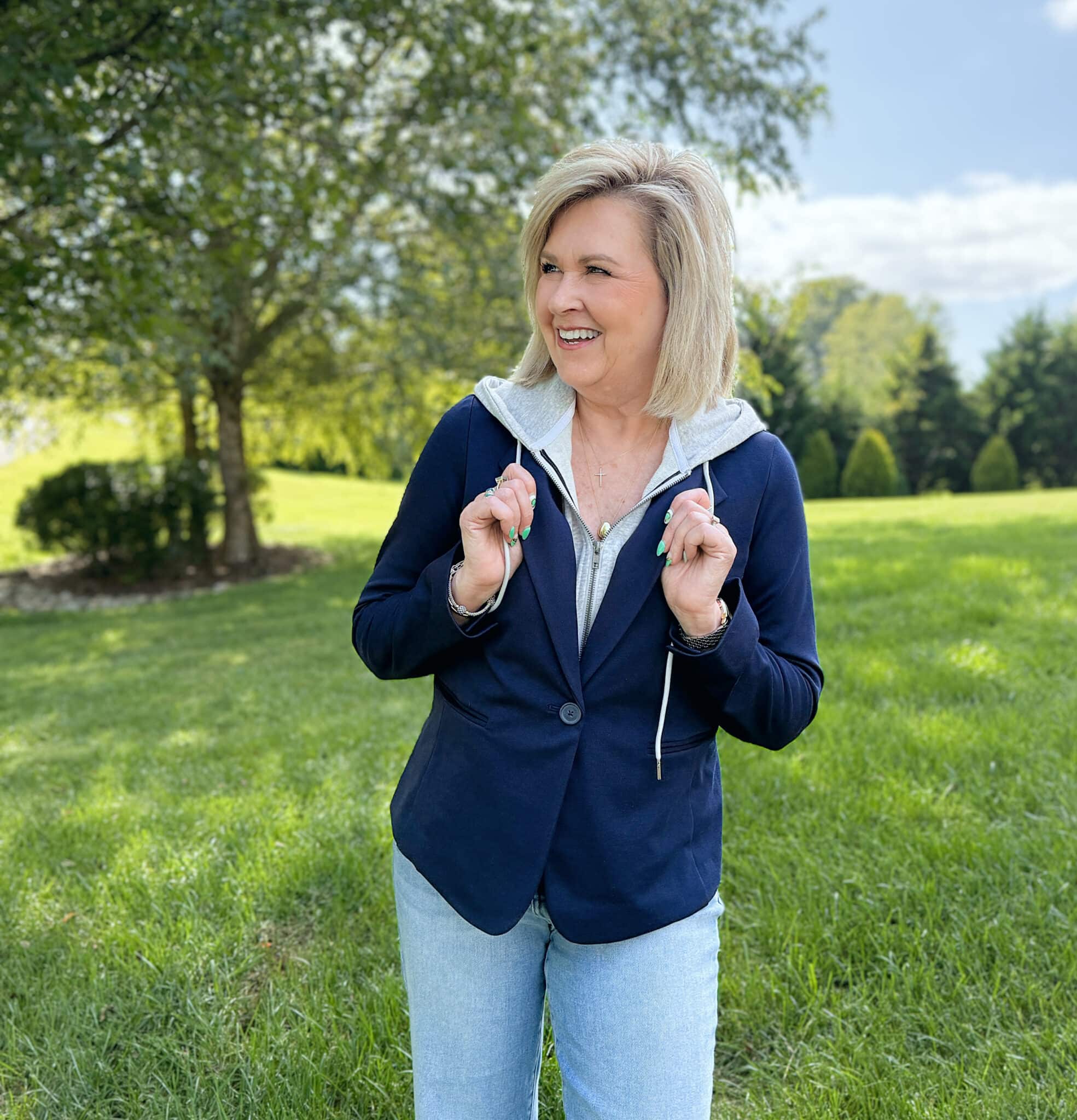 Woman over 50 standing in a grassy field in a buttoned navy and gray hoodie from Kohl's