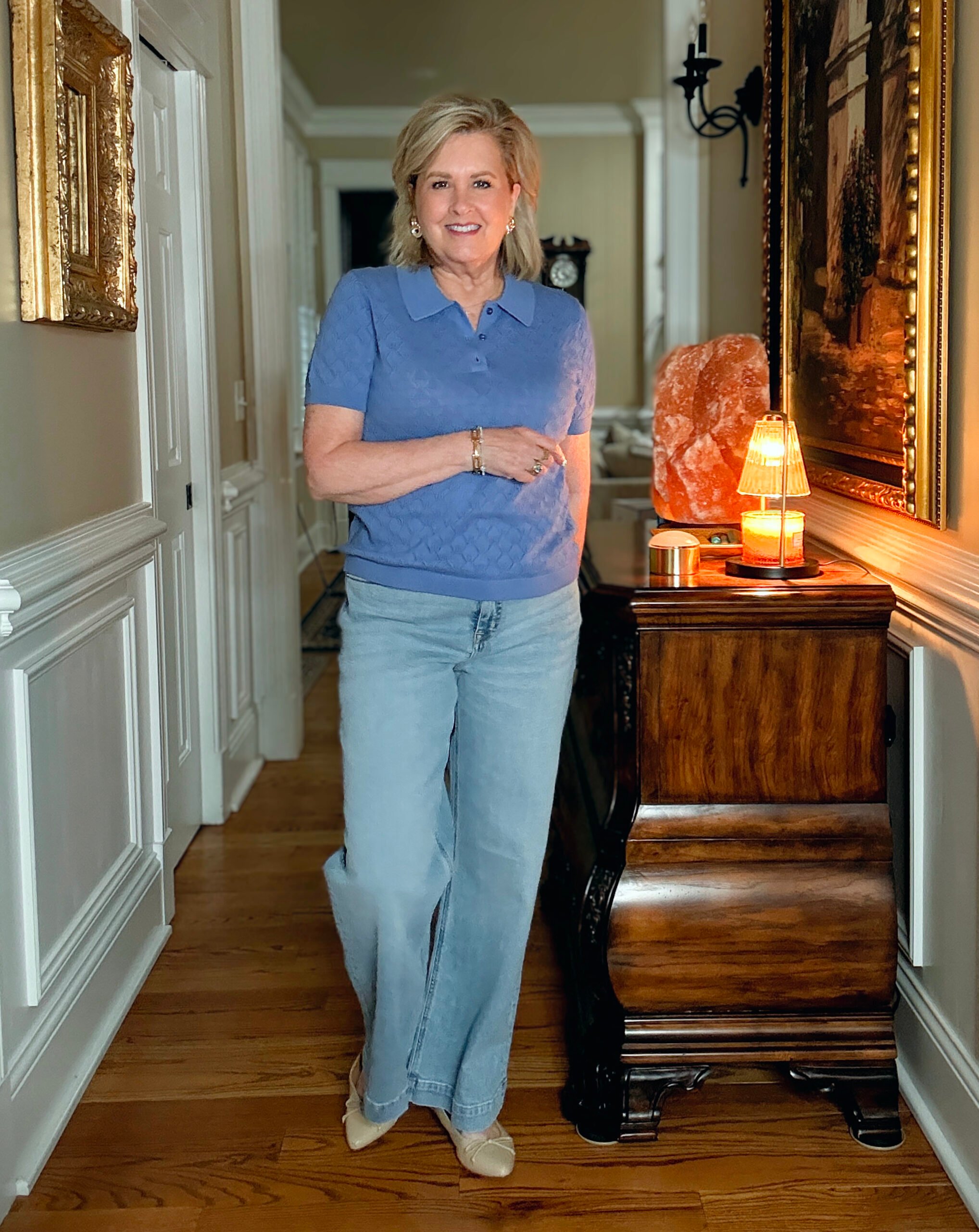 Tania Stephens in a hallway wearing a pointelle collared sweater and a pair of wide leg jeans