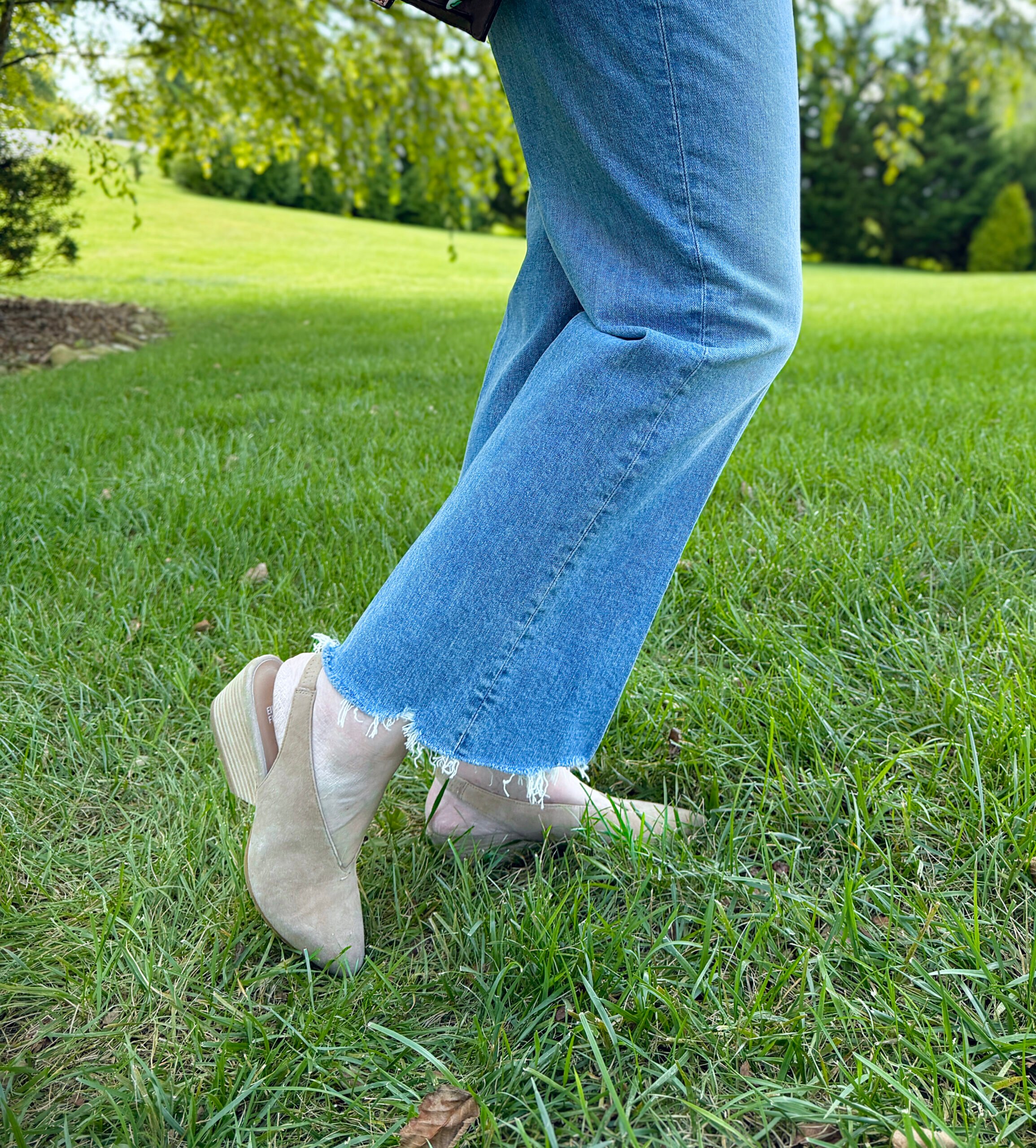 woman over 50 wearing frayed hem jeans with suede slingback pumps