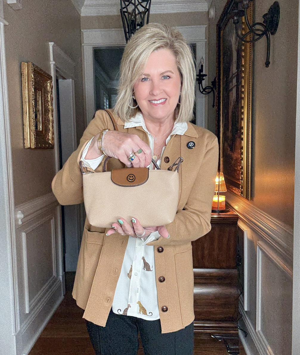 Tania wearing a cheetah button up shirt with a knit blazer, and a small handbag 