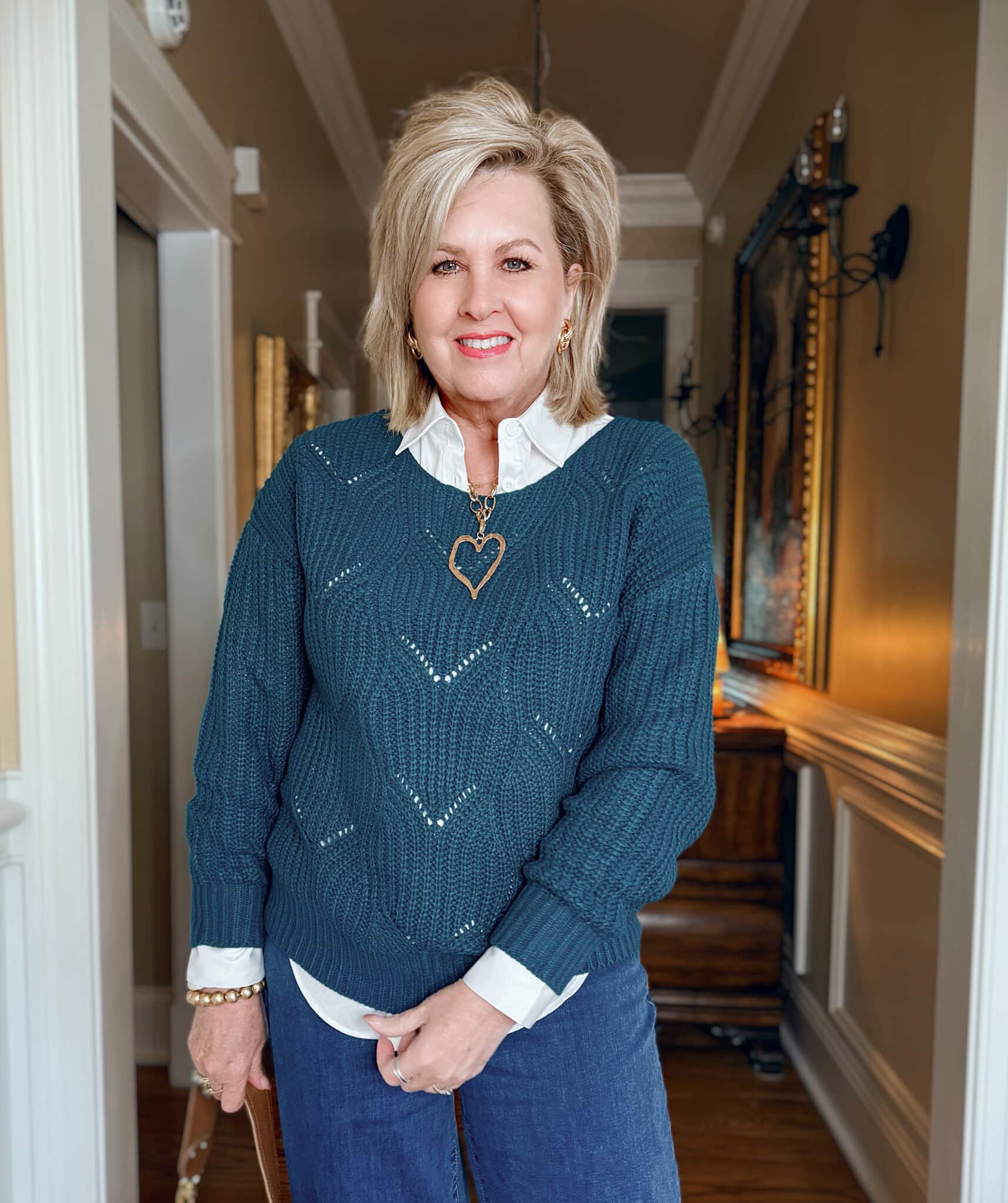 Tania is wearing an Amazon Teal Pointelle Sweater with a White Button Down Shirt and a large gold heart