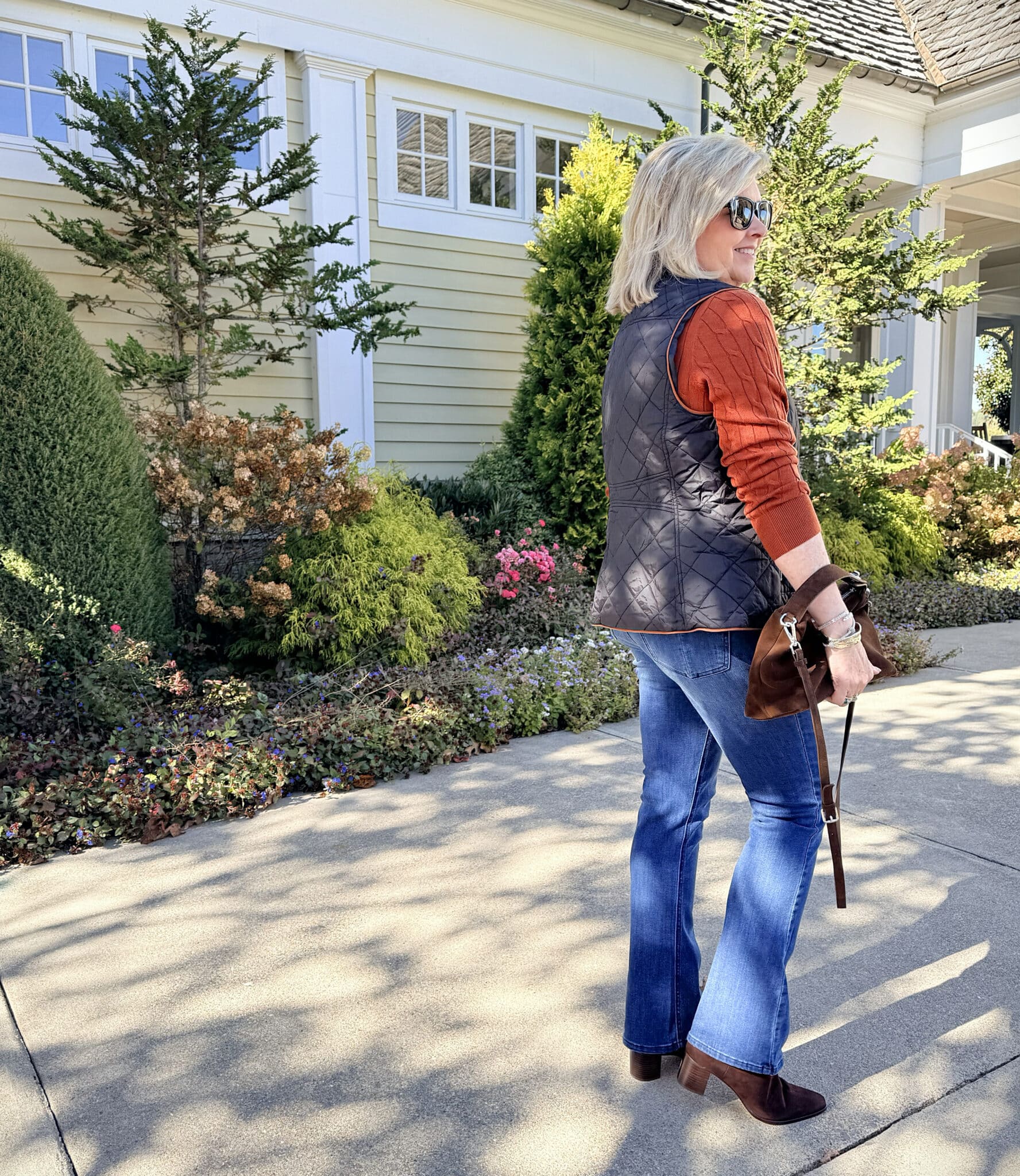 Amazon black vest with jeans and a brown handbag