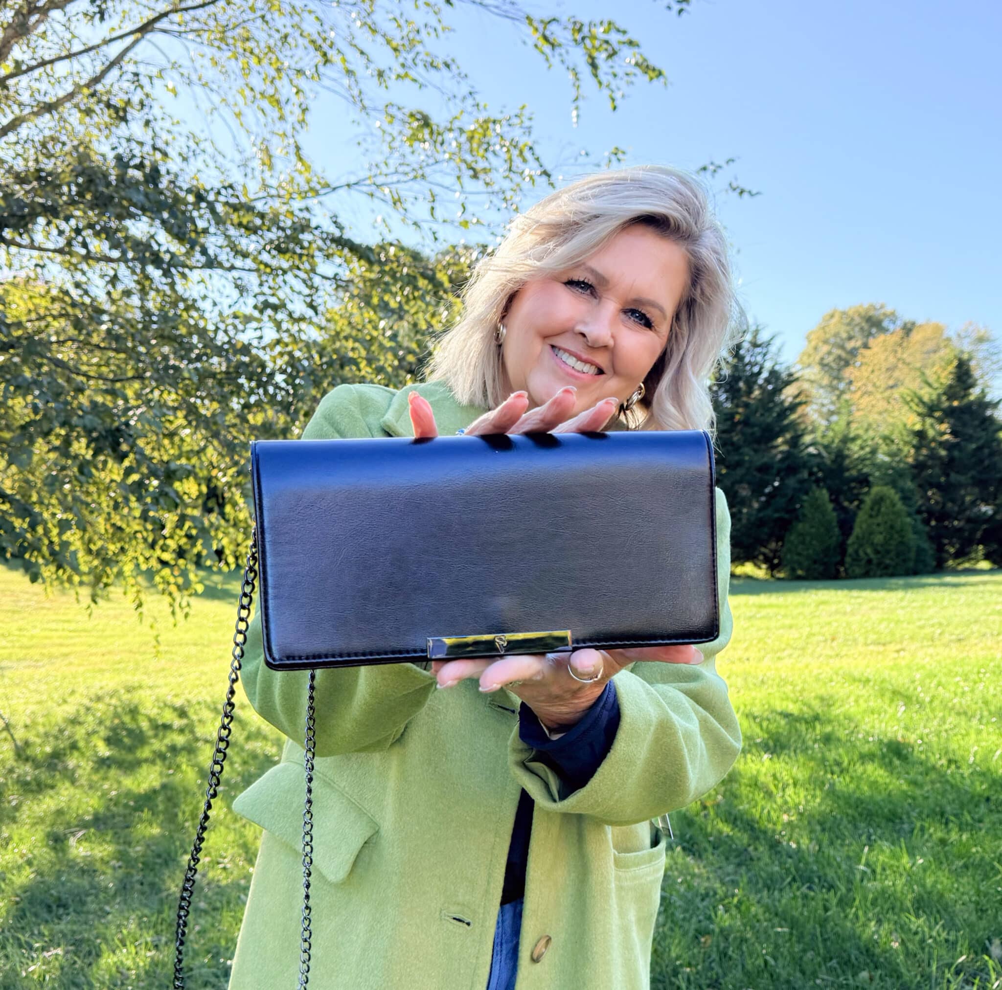 Tania Stephens standing under a tree with a Kohl's black envelope style clutch