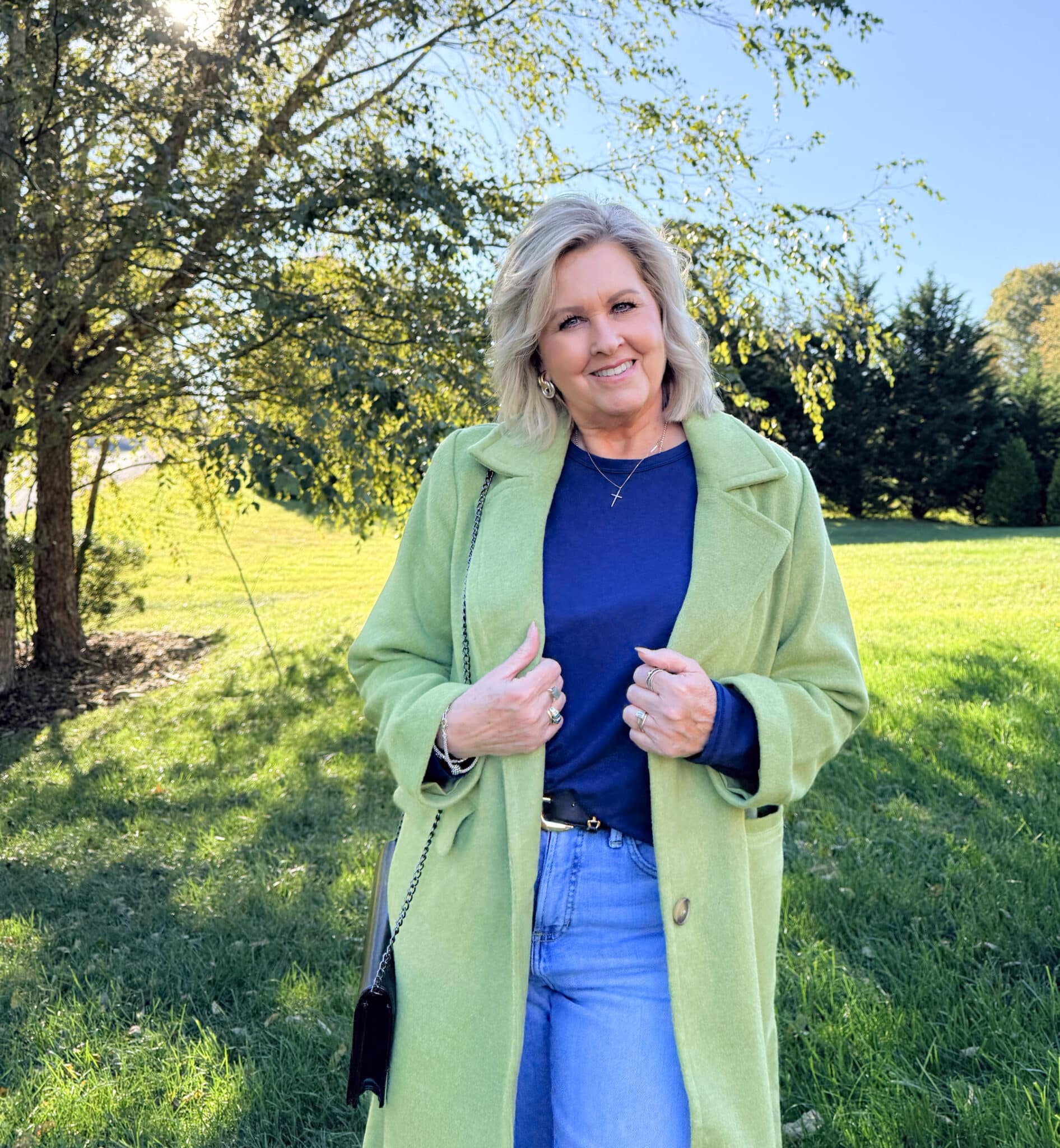 Tania Stephens standing under a tree wearing a Kohl's green coat with a navy tee and jeans