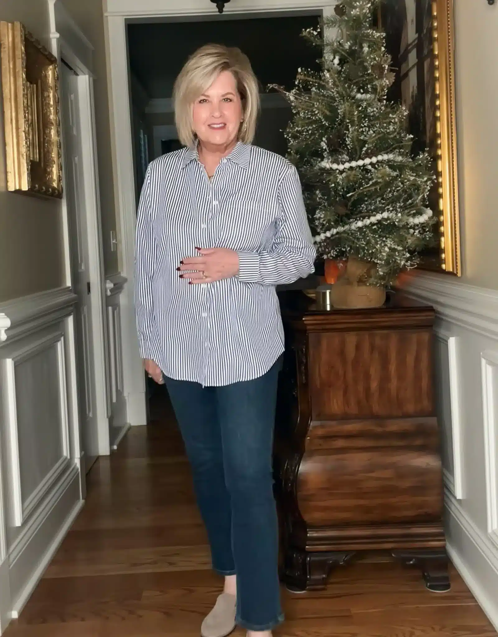Woman wearing a blue-and-white striped button-down shirt with jeans and taupe loafers, styled for a casual fall outfit.