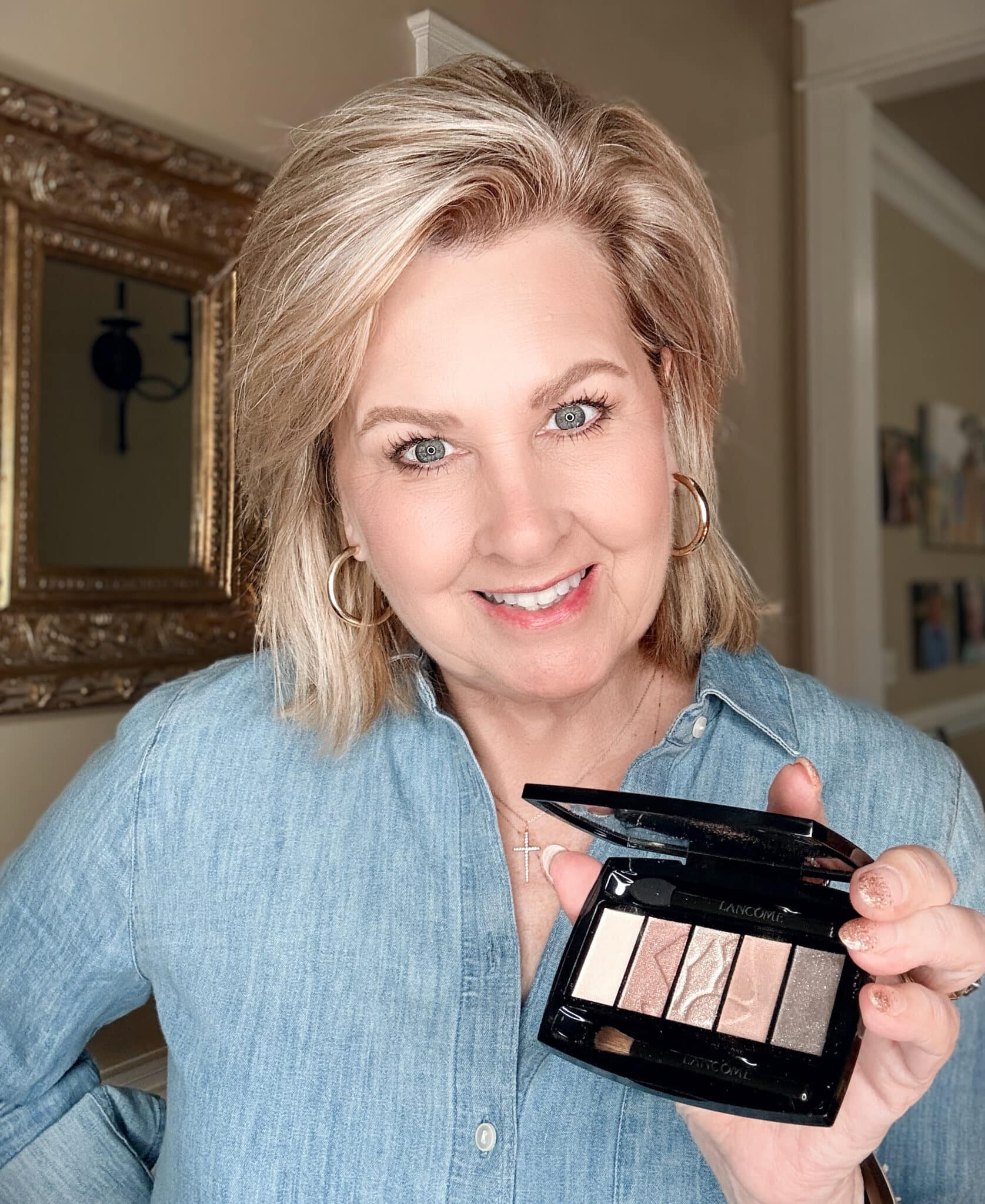Smiling woman showcasing the open Lancôme Color Design Eyeshadow Palette in Taupe Craze.