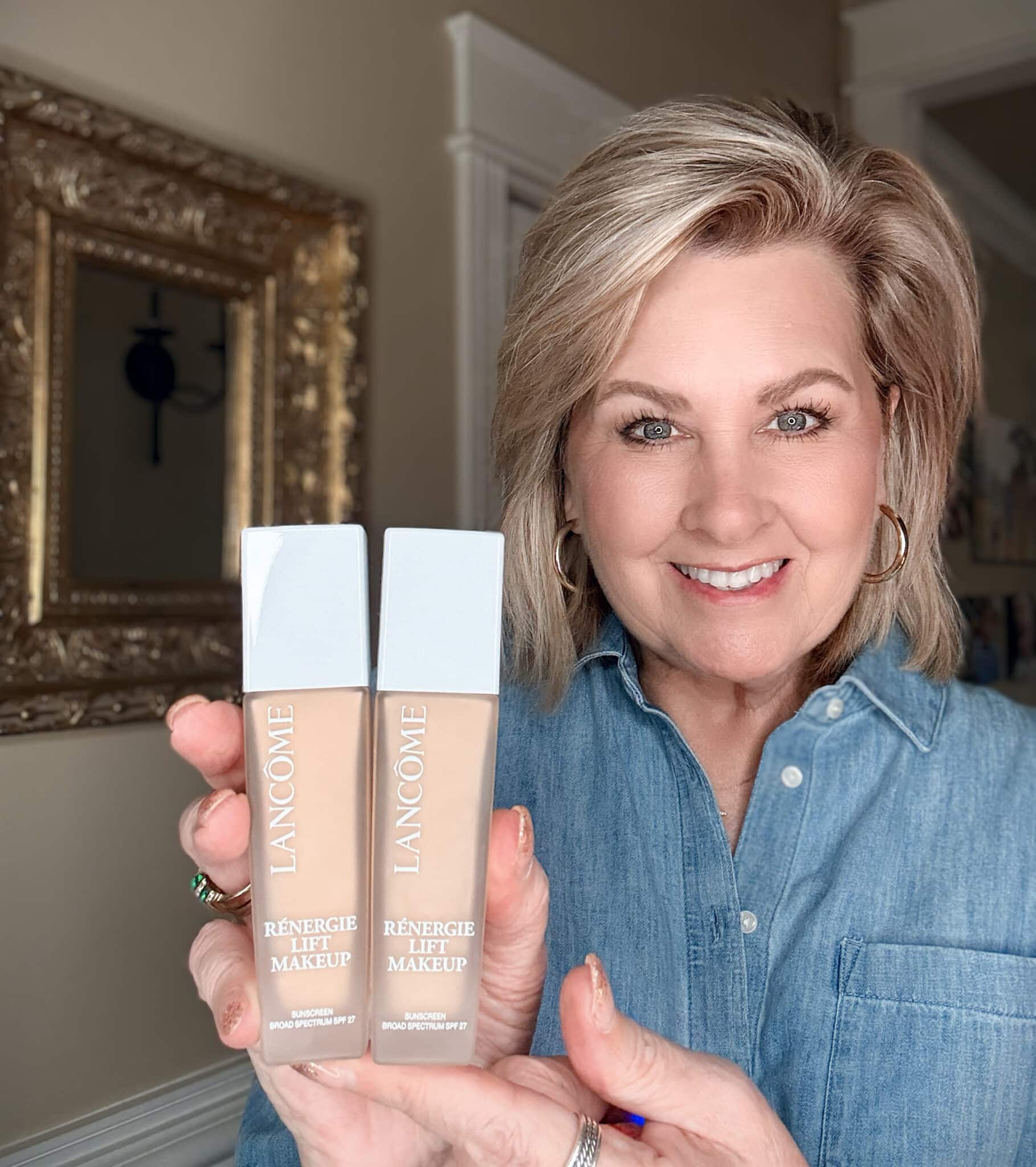 Woman holding up two bottles of Lancôme Rénergie Lift Makeup Foundation with SPF 27.