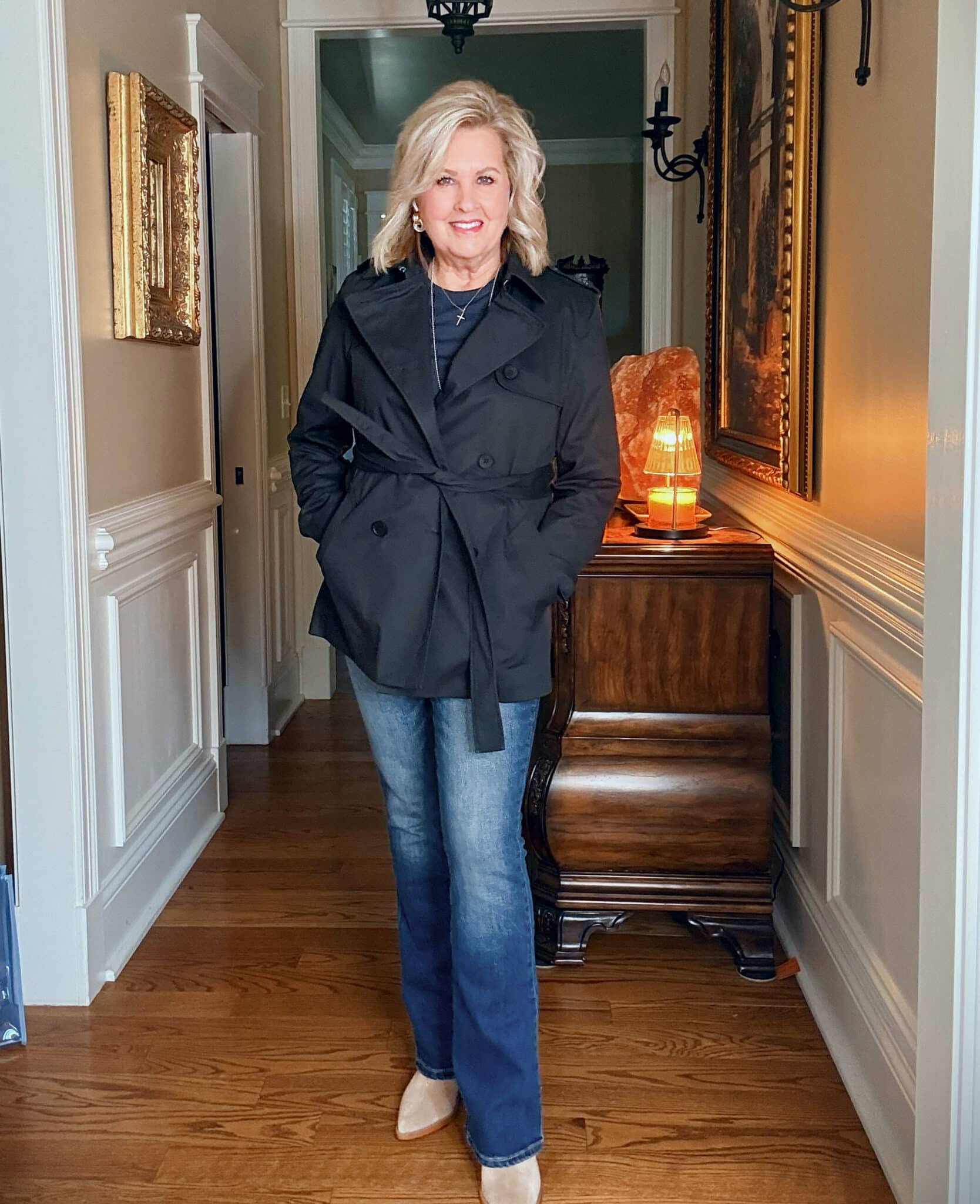 Tania wearing a navy tee and jeans with a black short trench jacket from Quince
