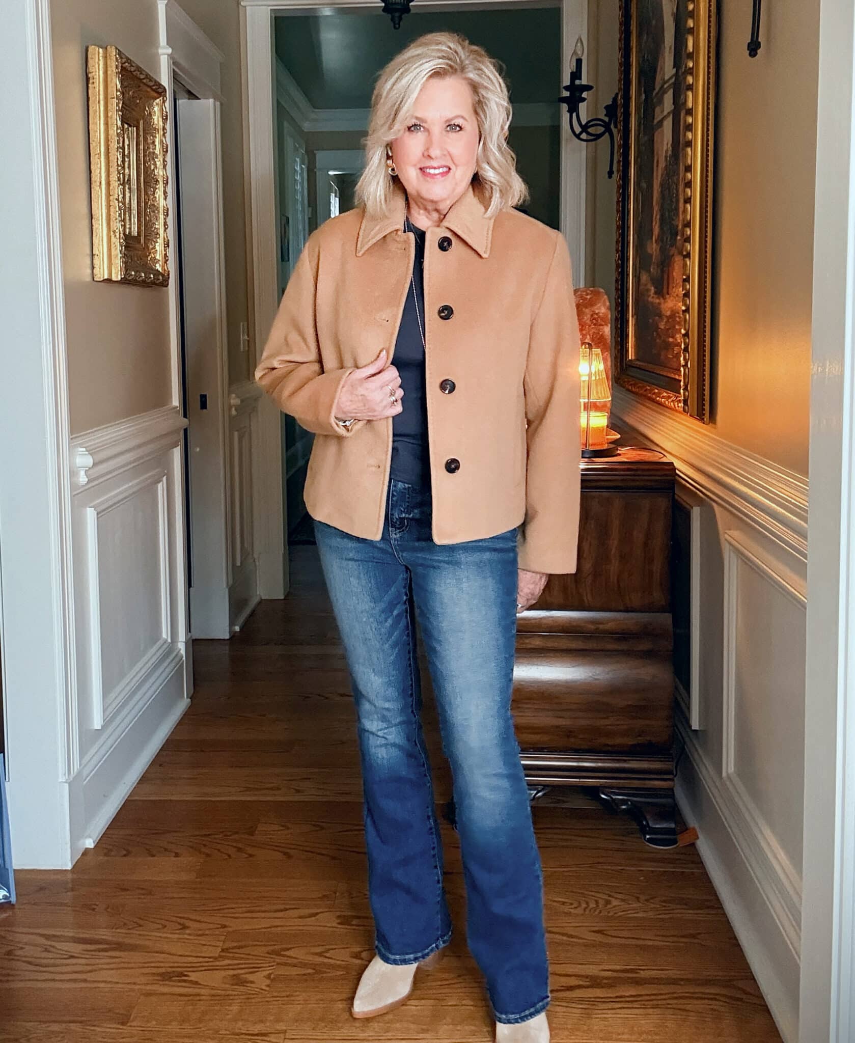Tania wearing a navy tee and jeans with a camel short jacket from Quince