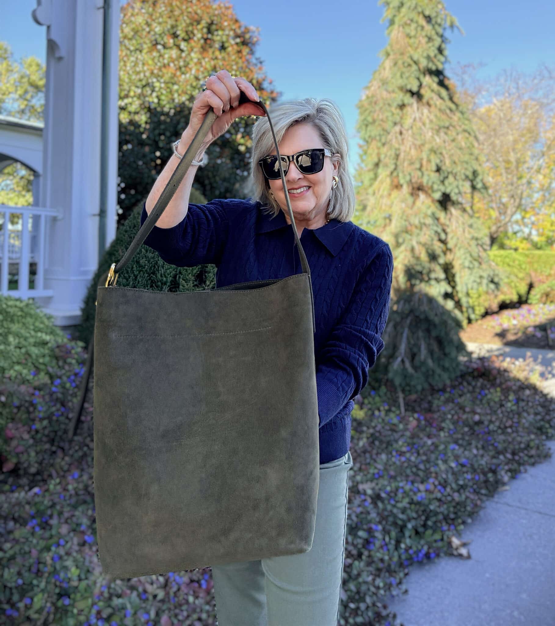 Tania wearing a navy sweater from Amazon and holding an olive Madewell handbag
