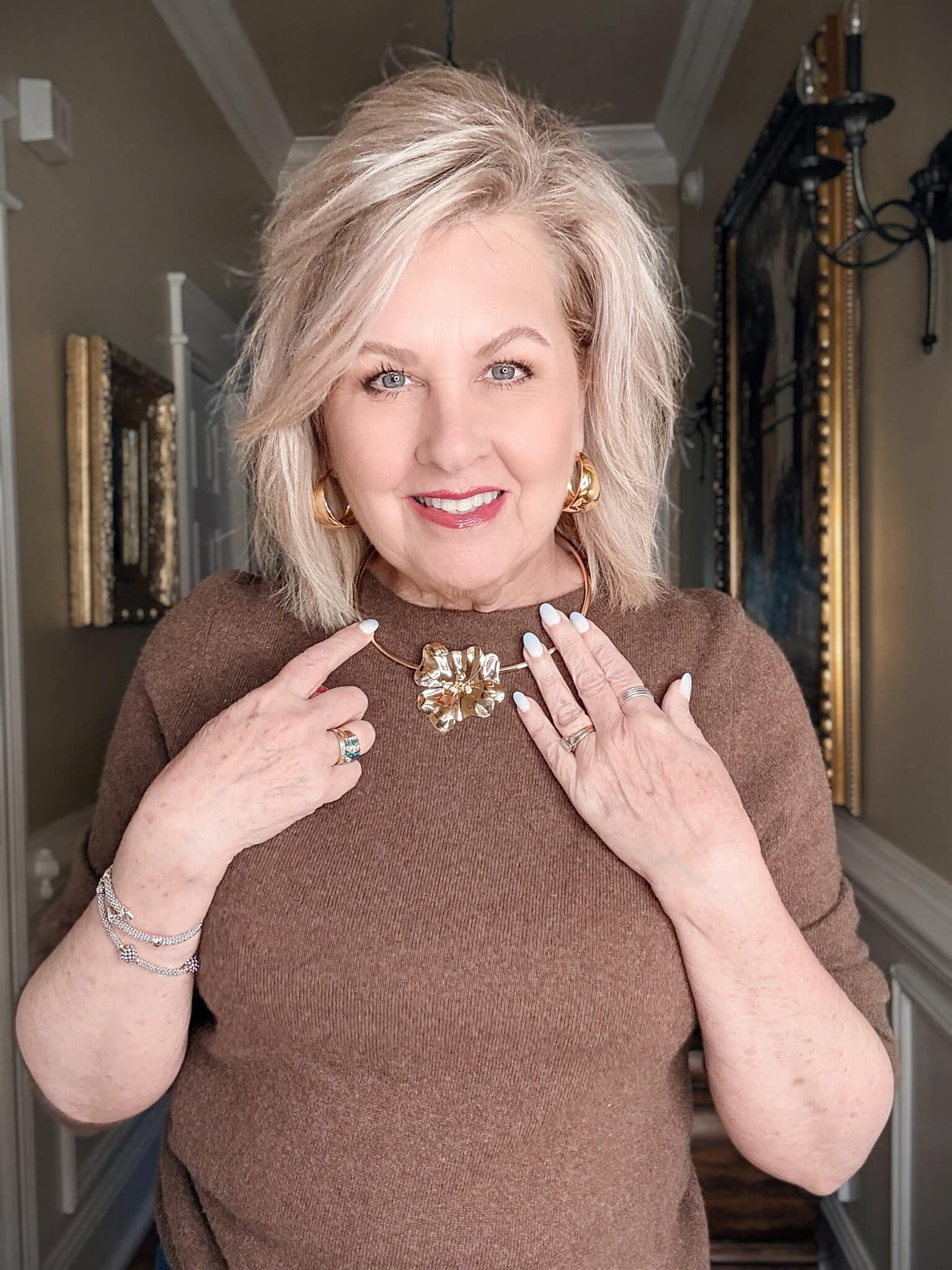 Hammered gold heart pendant necklace over a neutral sweater, a bold and sentimental statement jewelry piece.