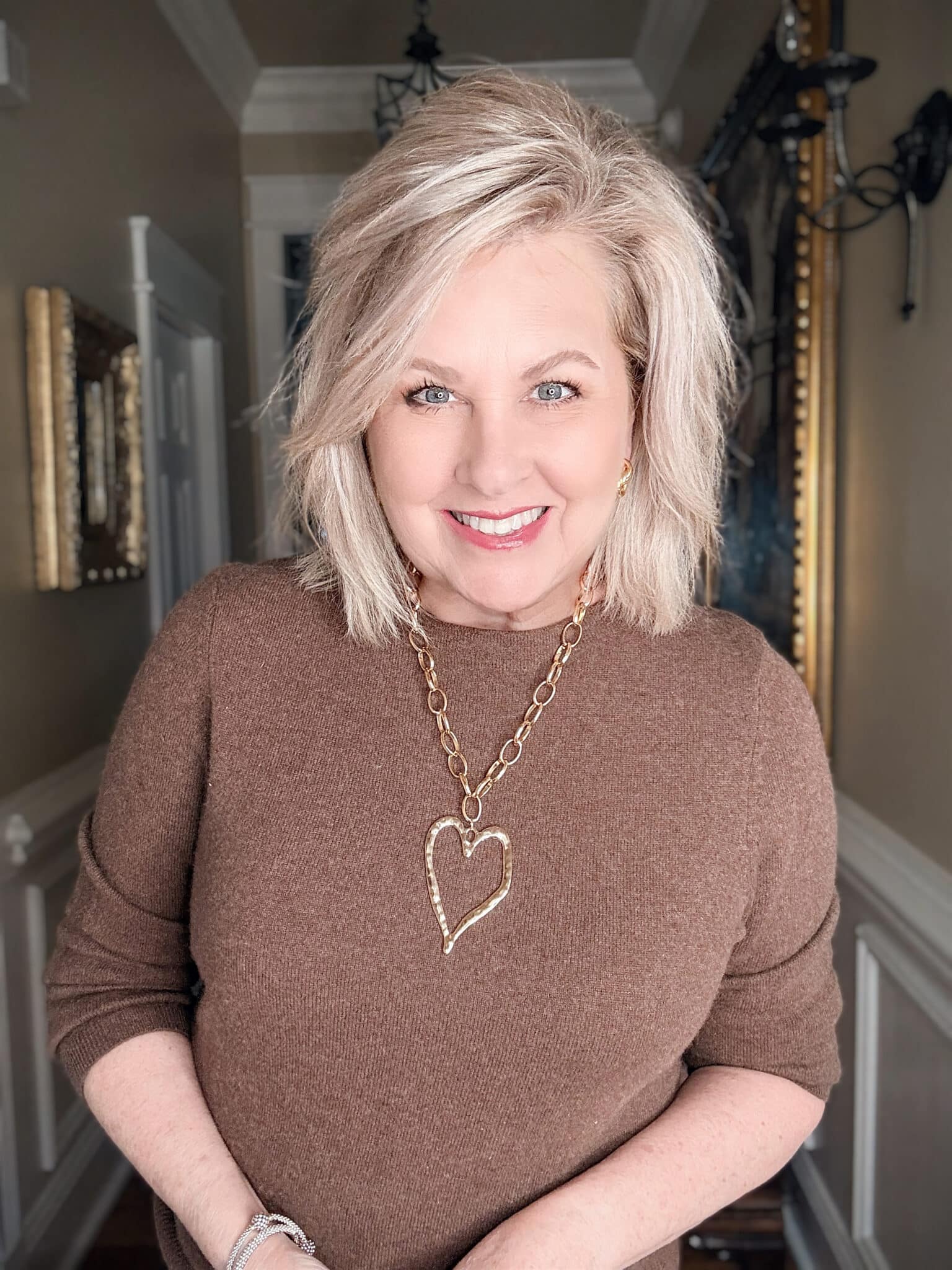 Gold coin pendant necklace on a short chain, adding a vintage-inspired statement to a simple sweater.