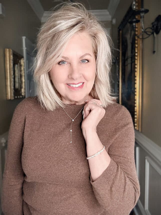 Woman in brown wearing a sparkly necklace and bracelet