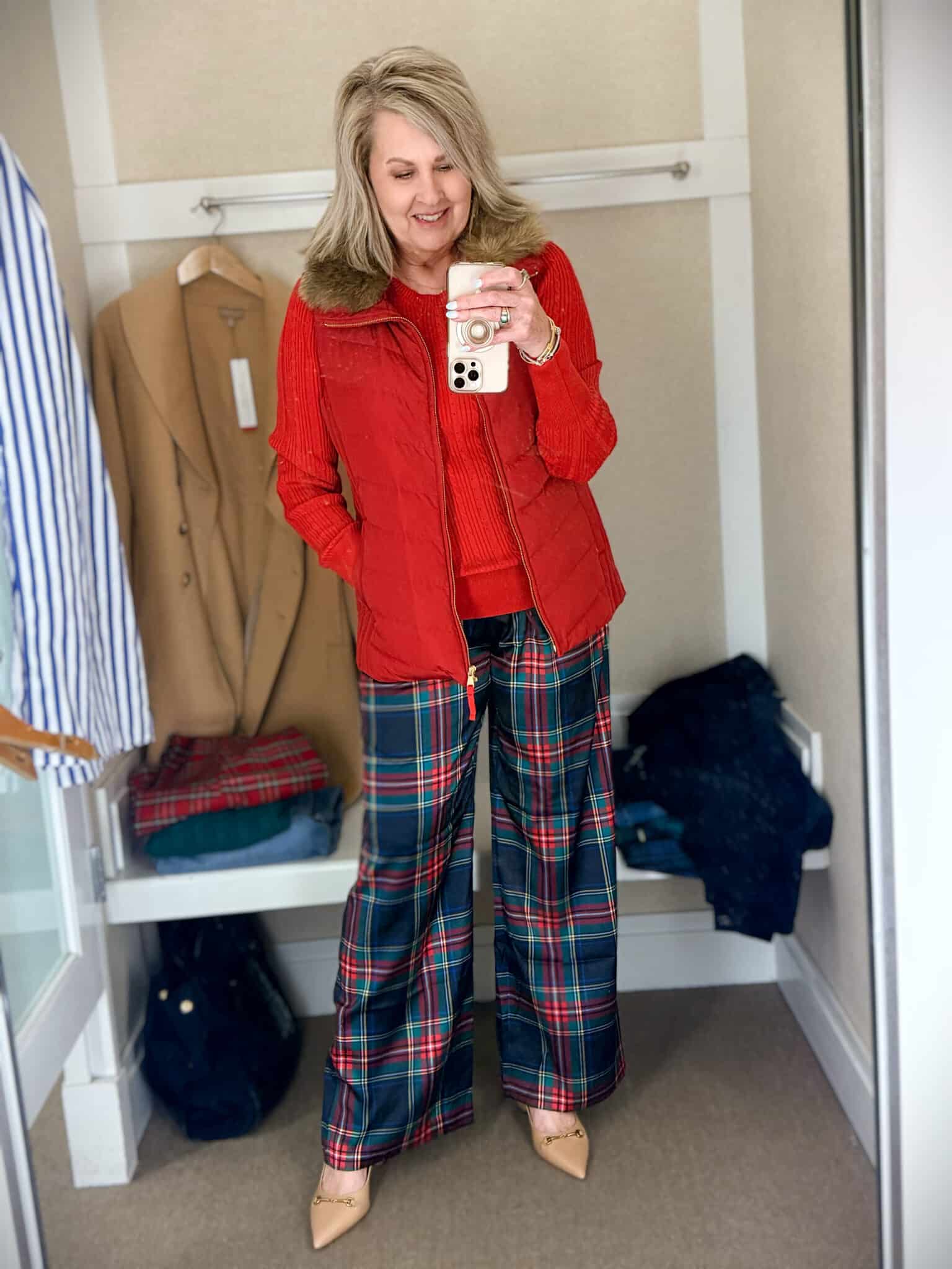 Tania trying on a green sweater with a red vest with a fur collar and blue and red plaid pants from Talbots