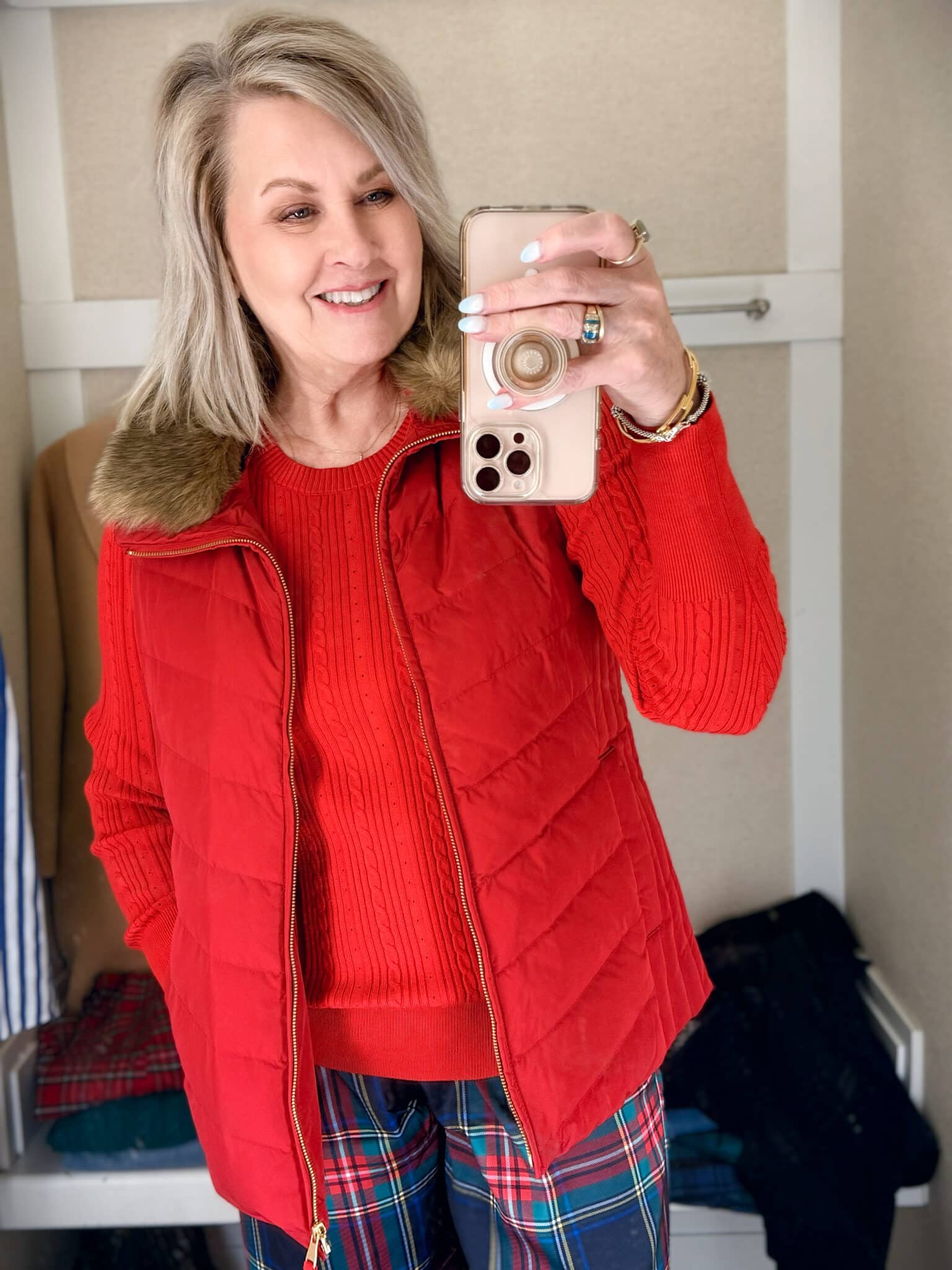 Tania trying on a green sweater with a red vest with a fur collar from Talbots