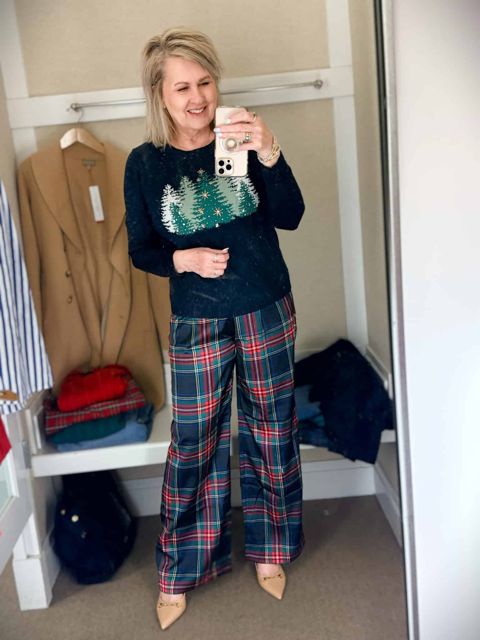 Tania trying on a navy sweater with green Christmas trees and blue and red plaid pants from Talbots