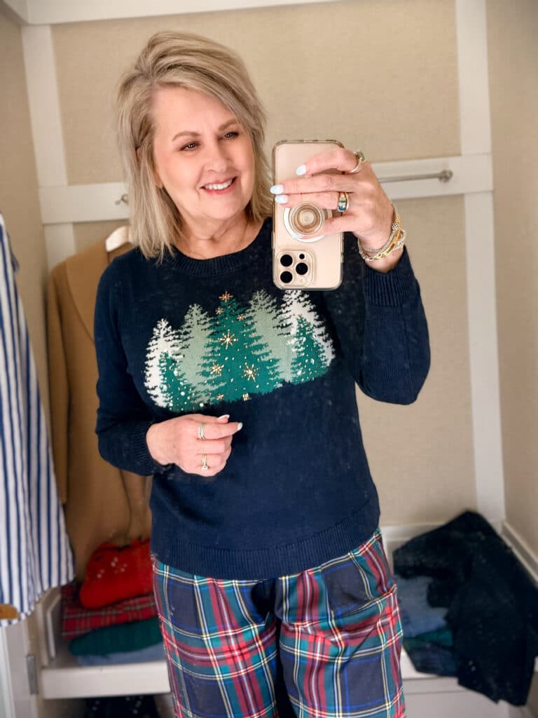 Tania trying on a navy sweater with green Christmas trees from Talbots