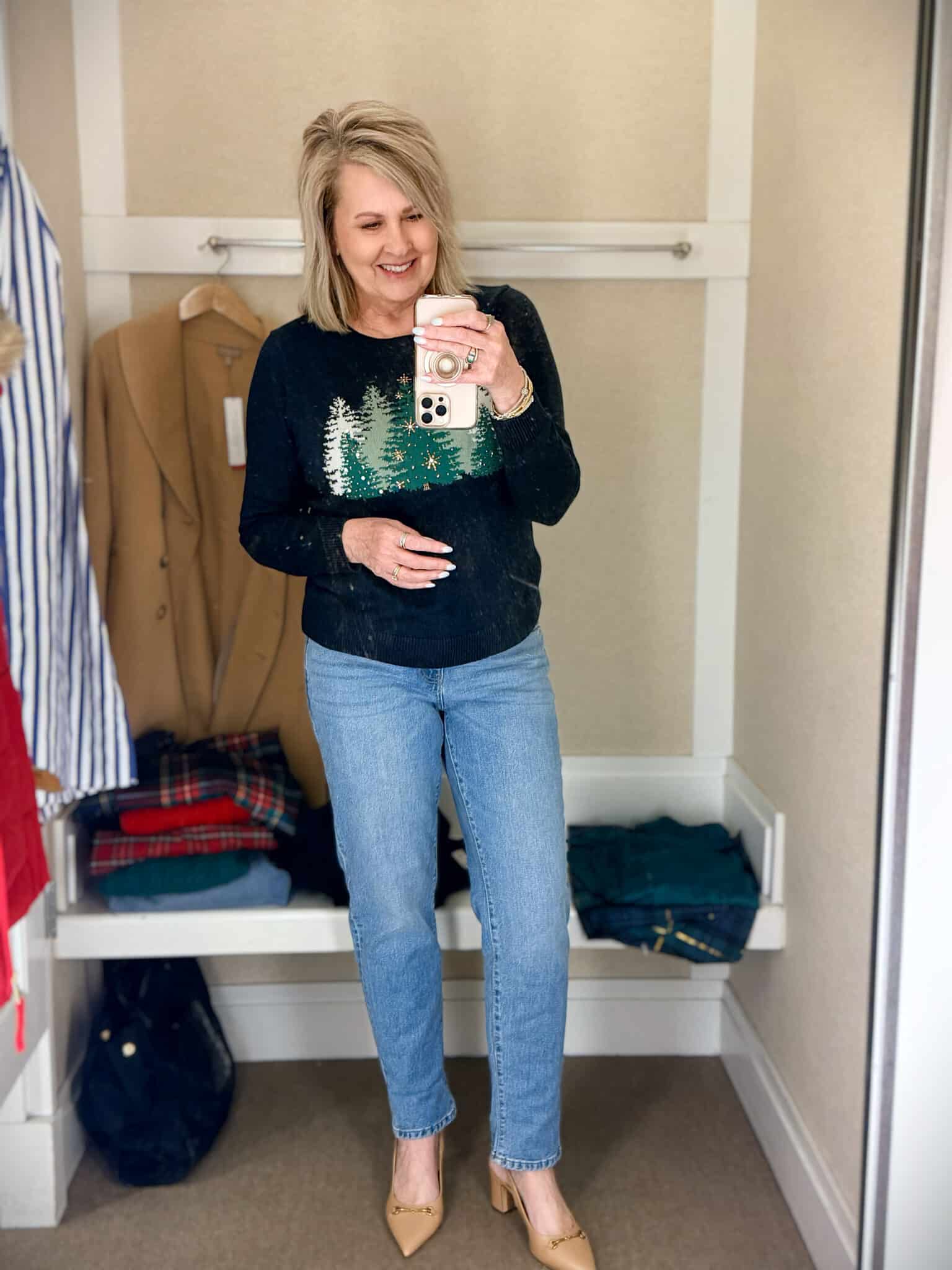 Tania trying on a navy sweater with green Christmas trees with light wash slim jeans from Talbots