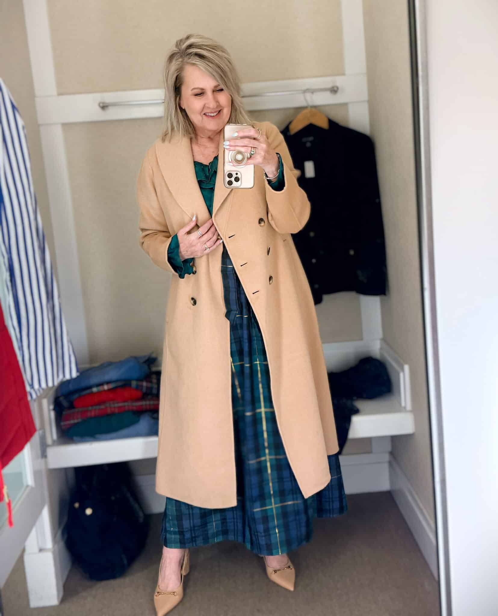 Tania trying on a camel double breasted long coat with a navy sweater with green Christmas trees with a navy velveteen blazer and a blue and green taffeta skirt from Talbots